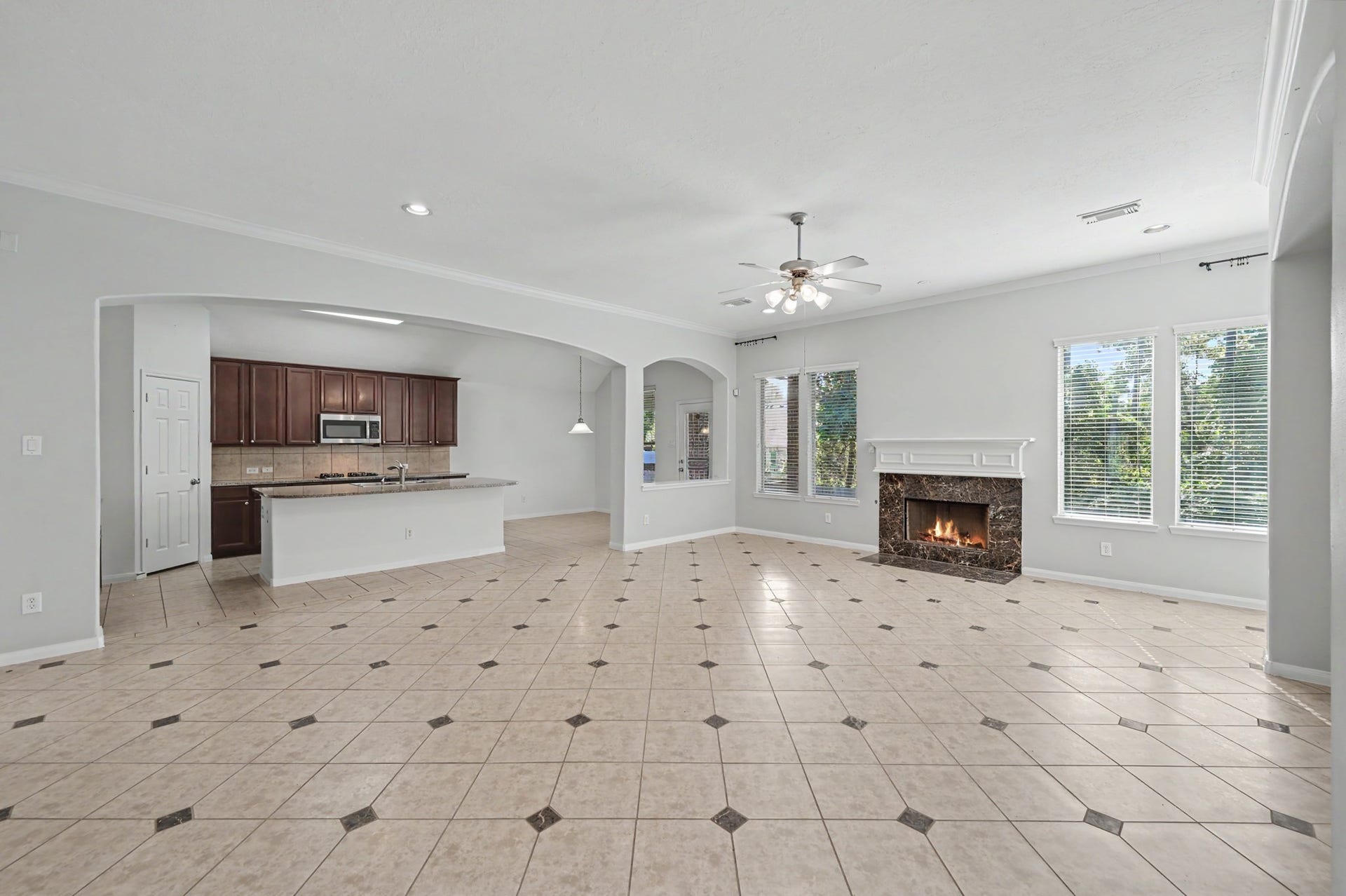 Expansive open-concept family room with cozy fireplace, decorative tile flooring and seamless flow into the spacious island kitchen and breakfast area.