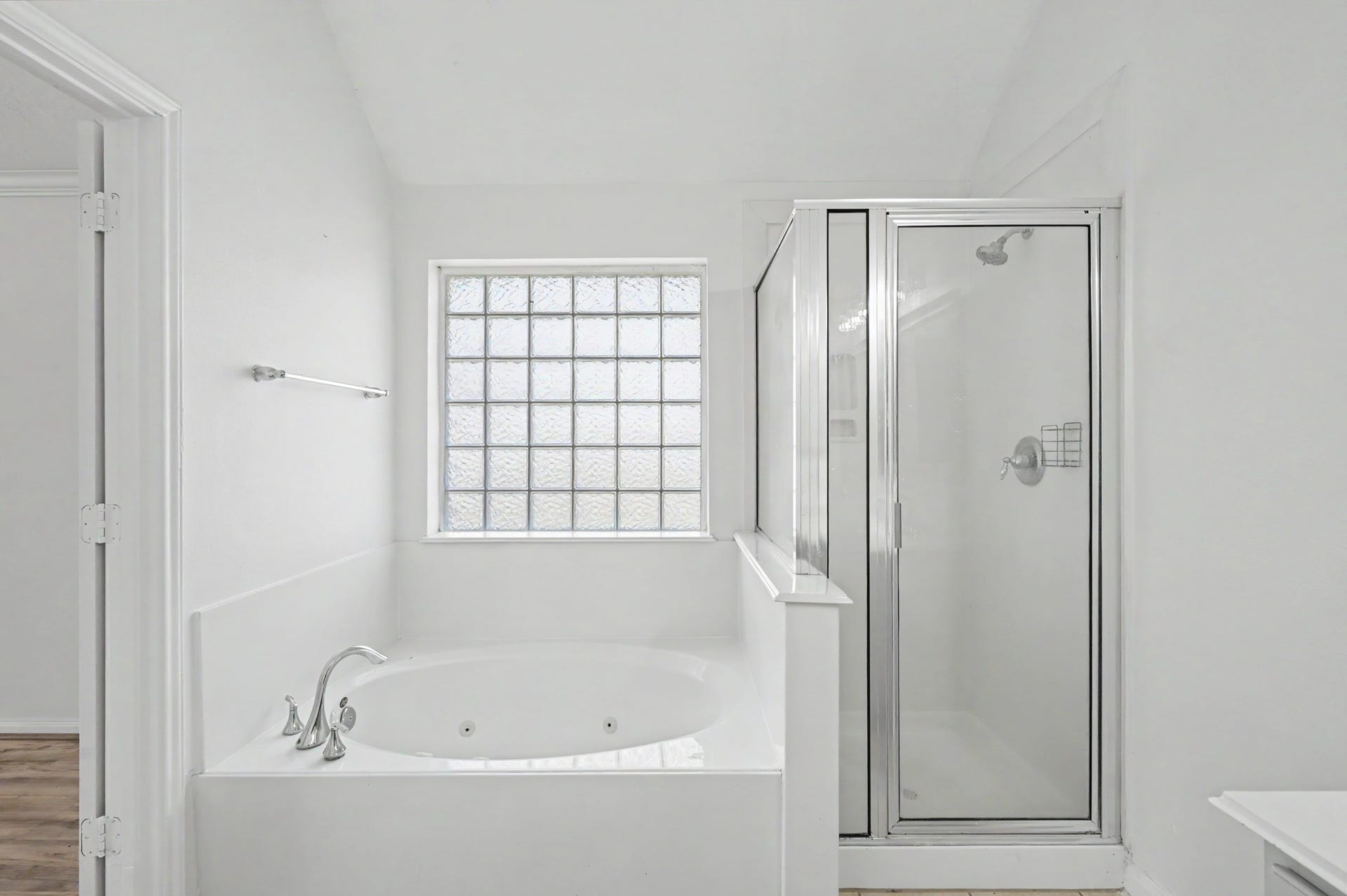 Primary bath featuring a relaxing jetted soaking tub, separate glass-enclosed shower and decorative glass block window.