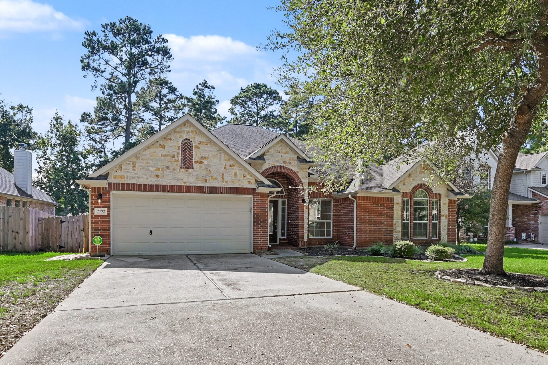 Beautiful D.R. Horton home featuring an attractive brick and stone exterior, charming covered entry, mature shade trees, manicured landscaping and an attached 2-car garage.