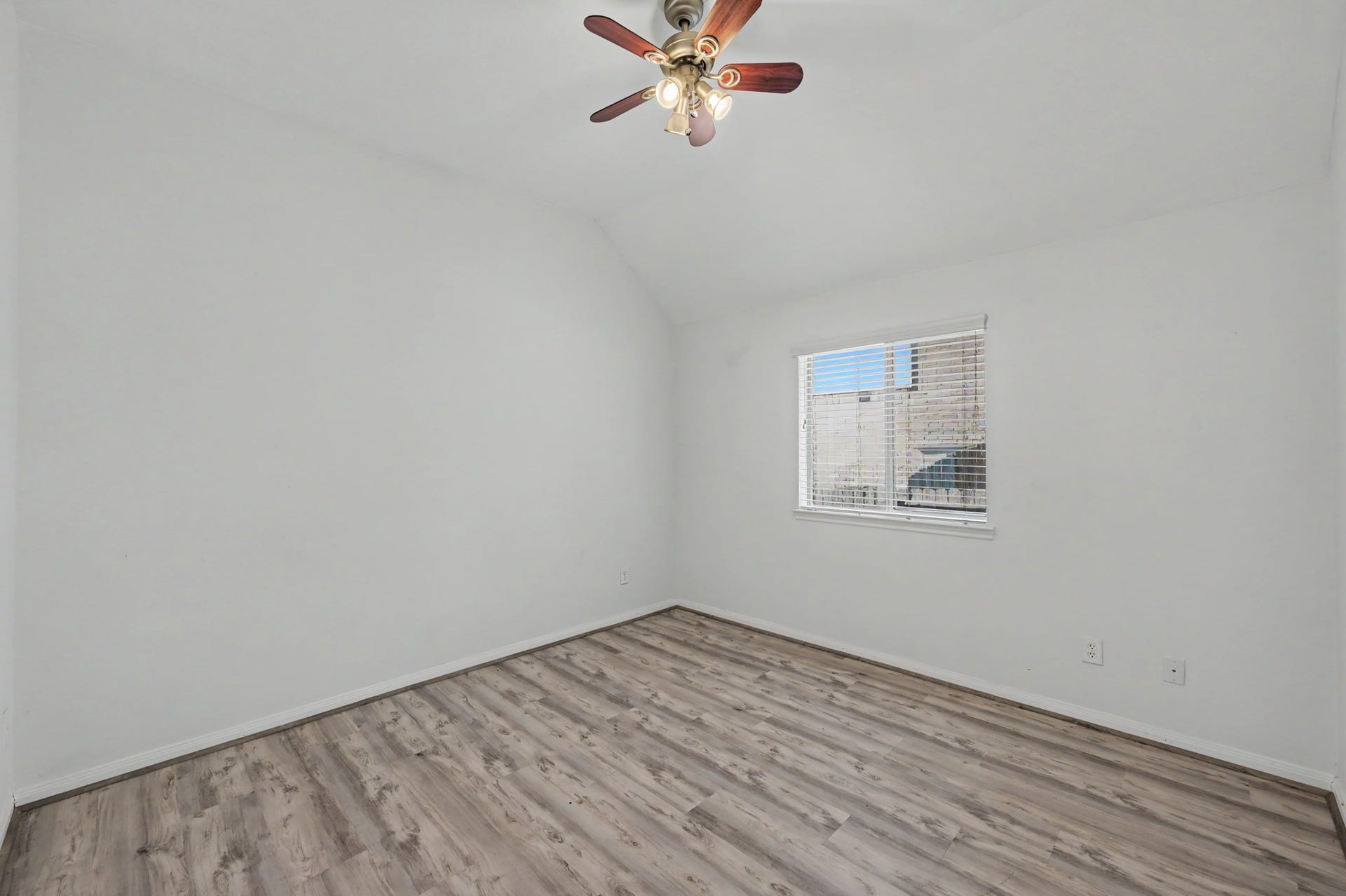 Generously sized secondary bedroom featuring wood-look flooring, ceiling fan and natural light.