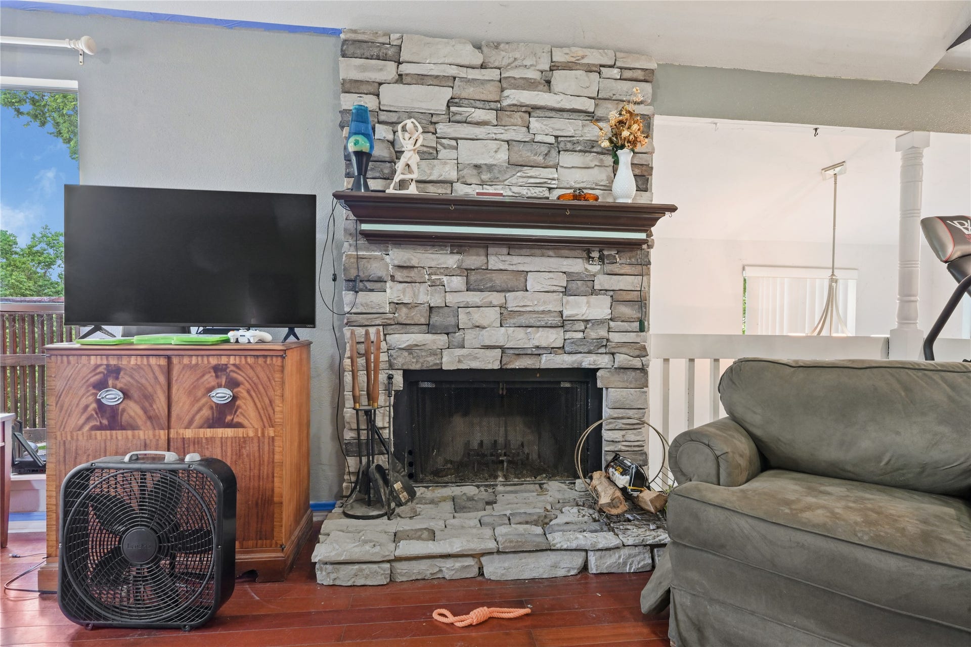 107 Harbour Town Lane, Conroe, TX 77356 Cozy focal point of the living room featuring a classic stone-accent fireplace with a rustic mantel.