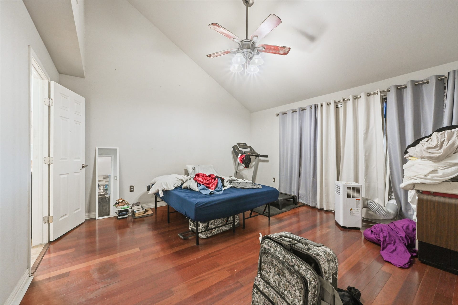107 Harbour Town Lane, Conroe, TX 77356 Expansive primary bedroom featuring warm wood-look flooring, high vaulted ceilings, a cooling ceiling fan, and generous floor space.