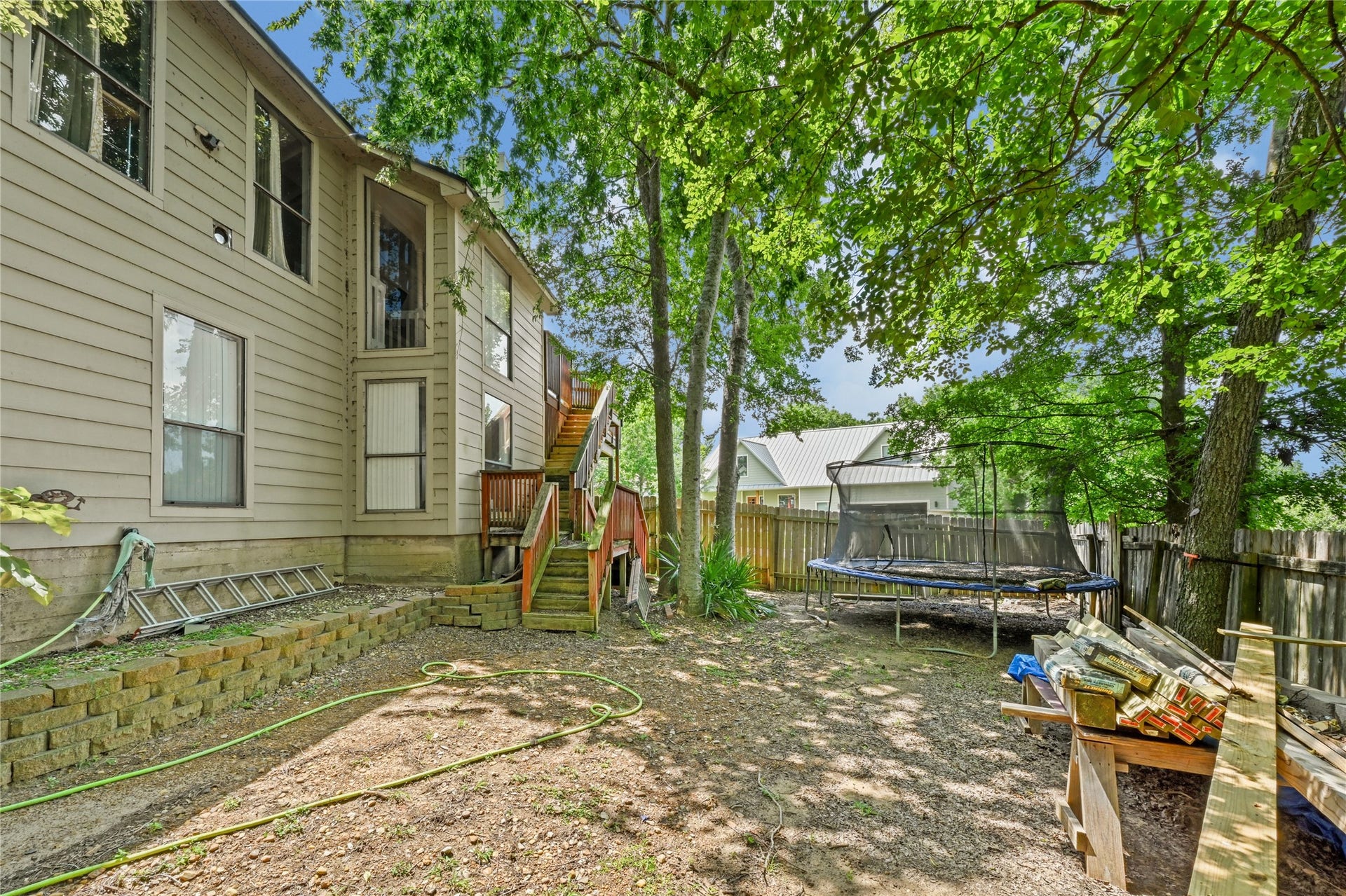 107 Harbour Town Lane, Conroe, TX 77356 An outdoor shot from the side yard featuring a brick and beige siding exterior of the home, bordered by a wooden fence and leafy green trees.