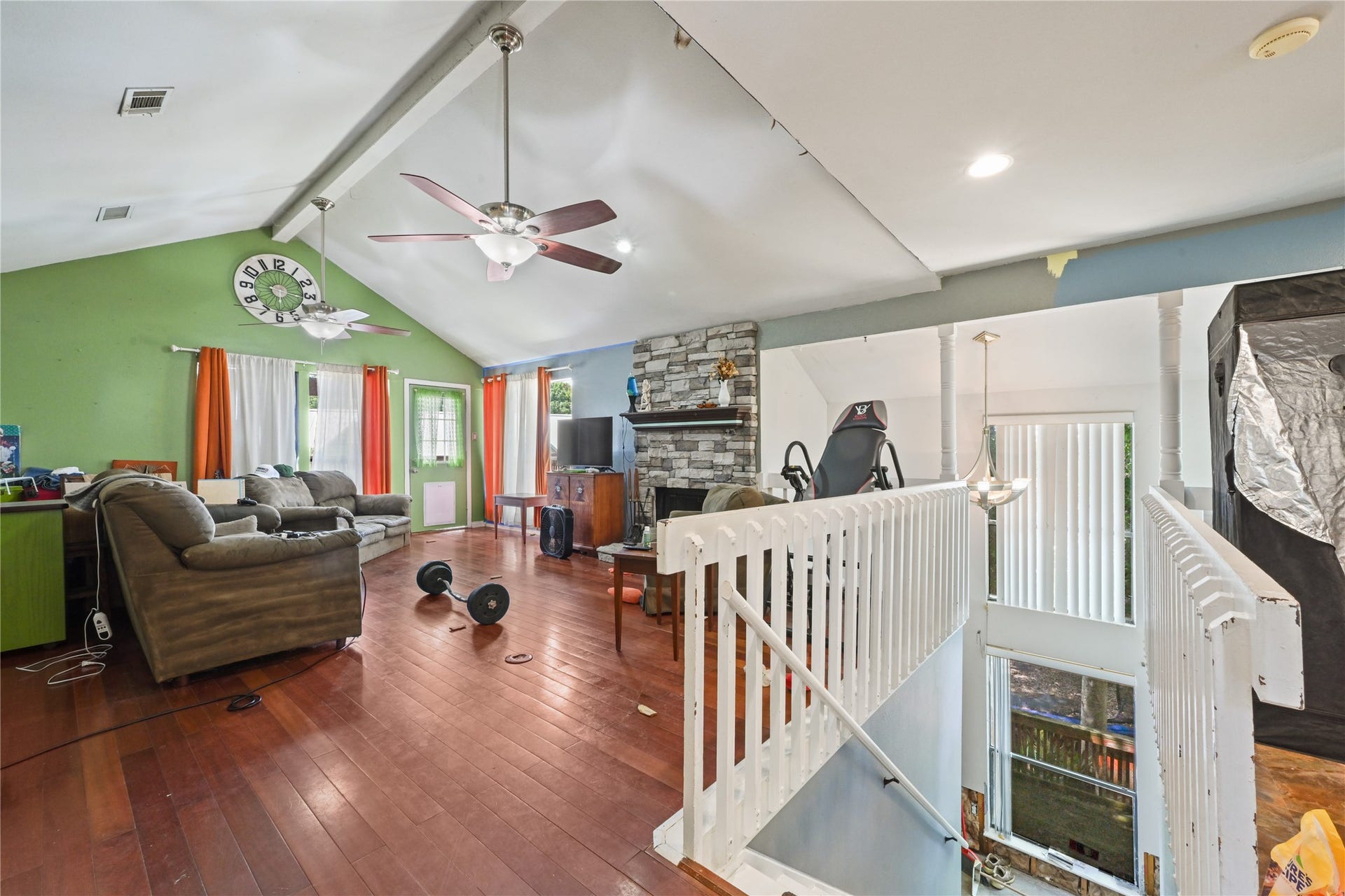107 Harbour Town Lane, Conroe, TX 77356 Impressive upper-level living room boasting rich wood-look flooring, soaring vaulted ceilings with a fan, and an open railing overlooking the stairs.