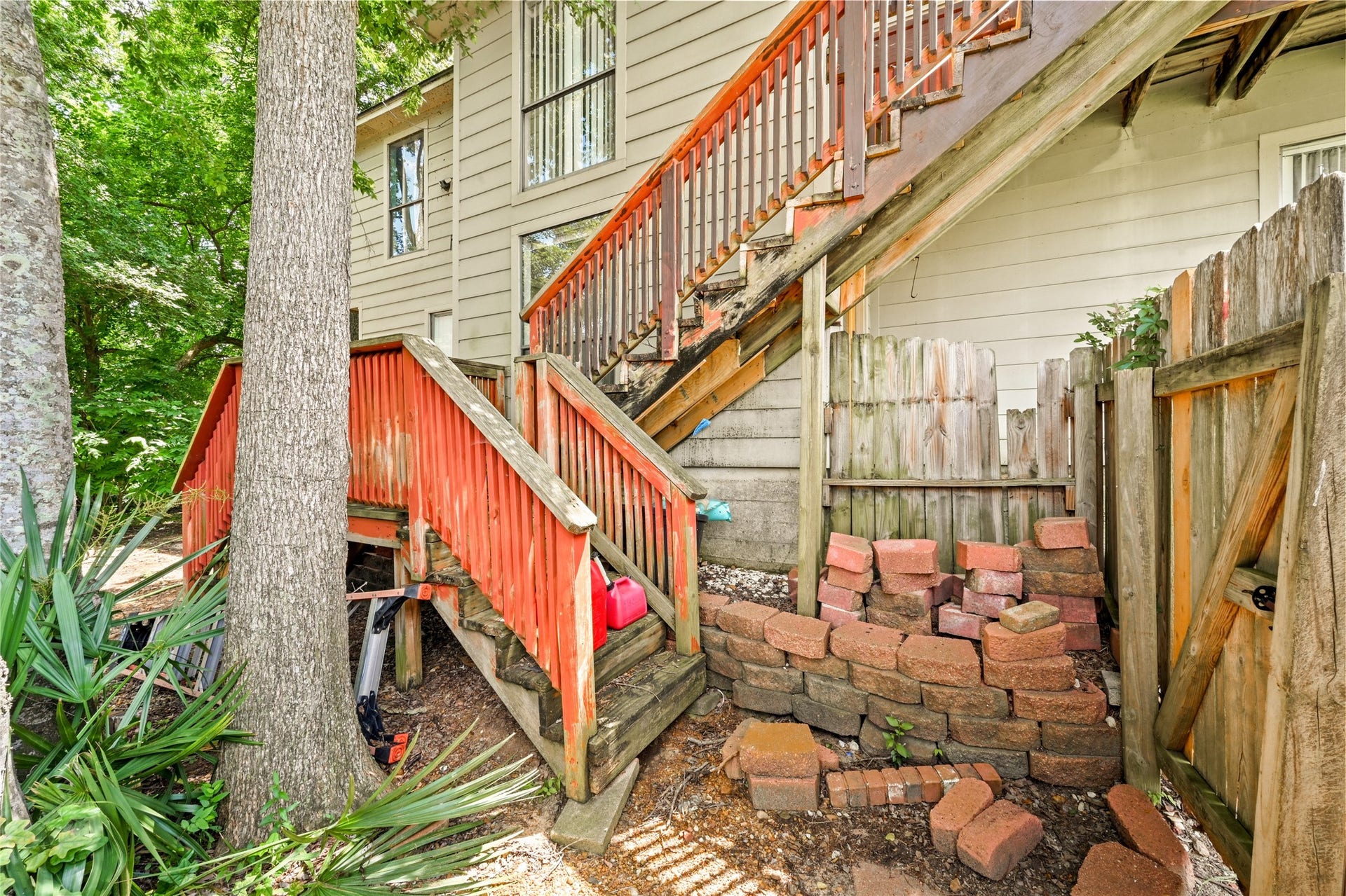 107 Harbour Town Lane, Conroe, TX 77356 Close-up of the exterior wooden staircase leading up to the main levels, accented by natural stone landscaping elements.
