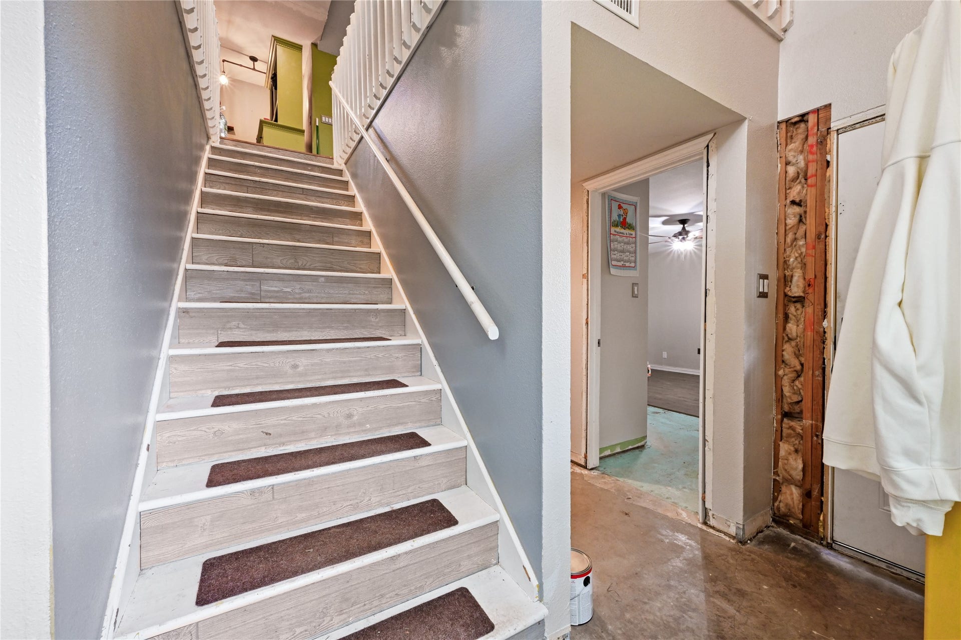 107 Harbour Town Lane, Conroe, TX 77356 Striking view of the central staircase leading up to the main living areas, paired with a glimpse of the adjacent hallway layout.