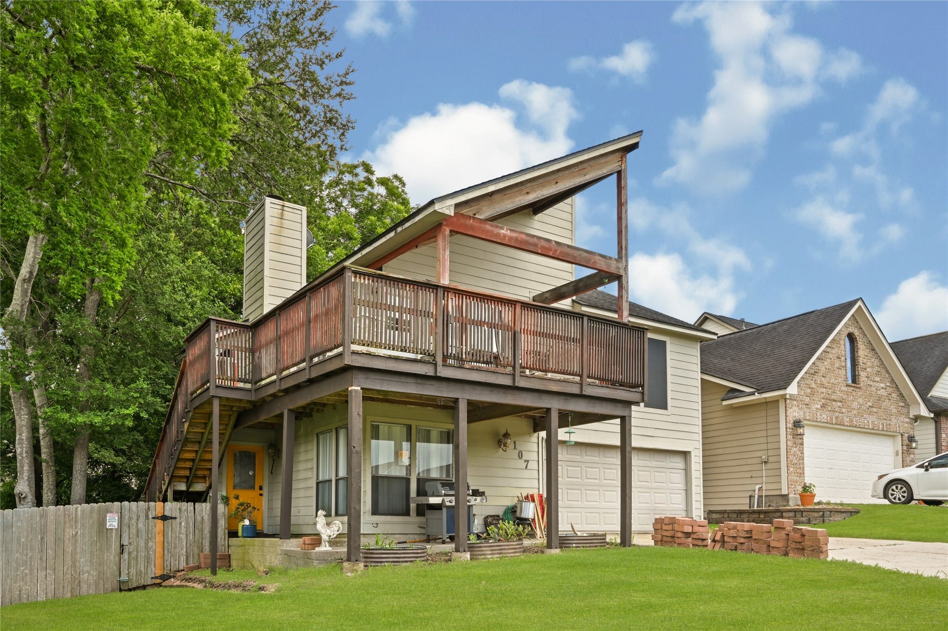 107 Harbour Town Lane, Conroe, TX 77356 Side profile view of the property showing the expansive multi-level deck structure and surrounding green lawn.