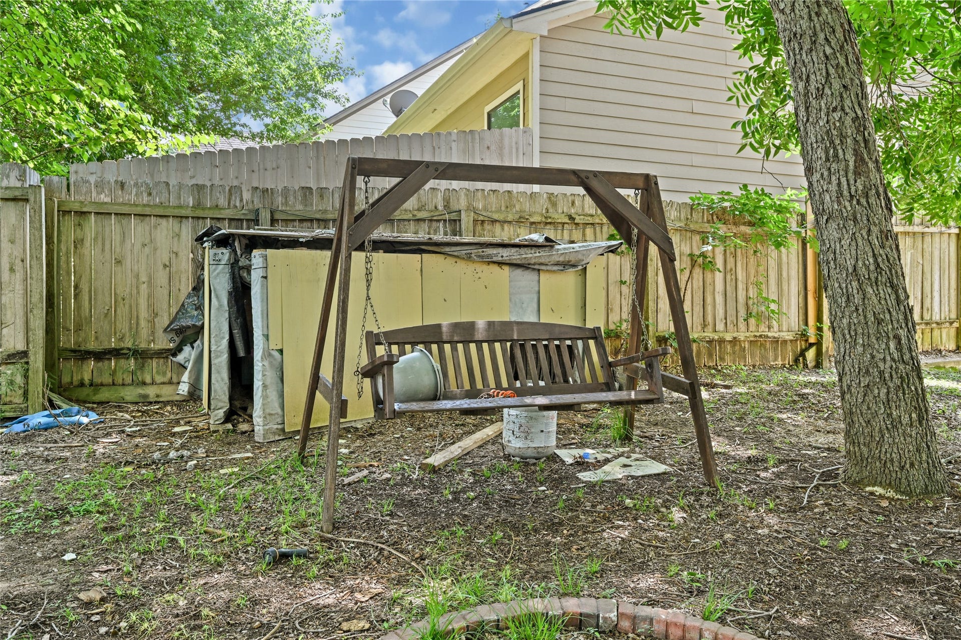 107 Harbour Town Lane, Conroe, TX 77356 A backyard scene featuring an A-frame swing set on the lawn, with a detached shed and a wooden privacy fence in the background.