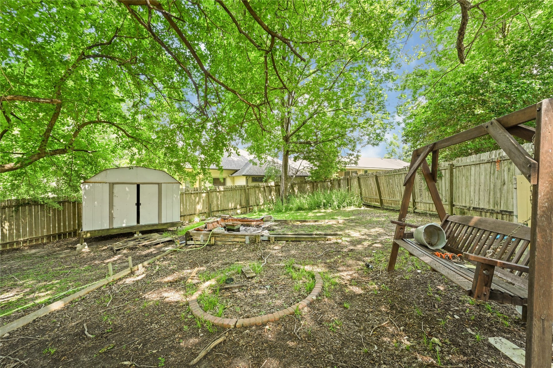 107 Harbour Town Lane, Conroe, TX 77356 A wide view of the grassy backyard area featuring an outdoor swing set, a white storage shed, and mature green trees providing shade.