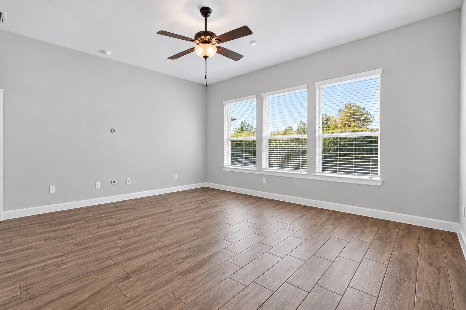 1515 Shining Willow Court, Richmond, TX 77406 Spacious primary bedroom featuring high ceilings, abundant natural light, and beautiful wood-look tile flooring.