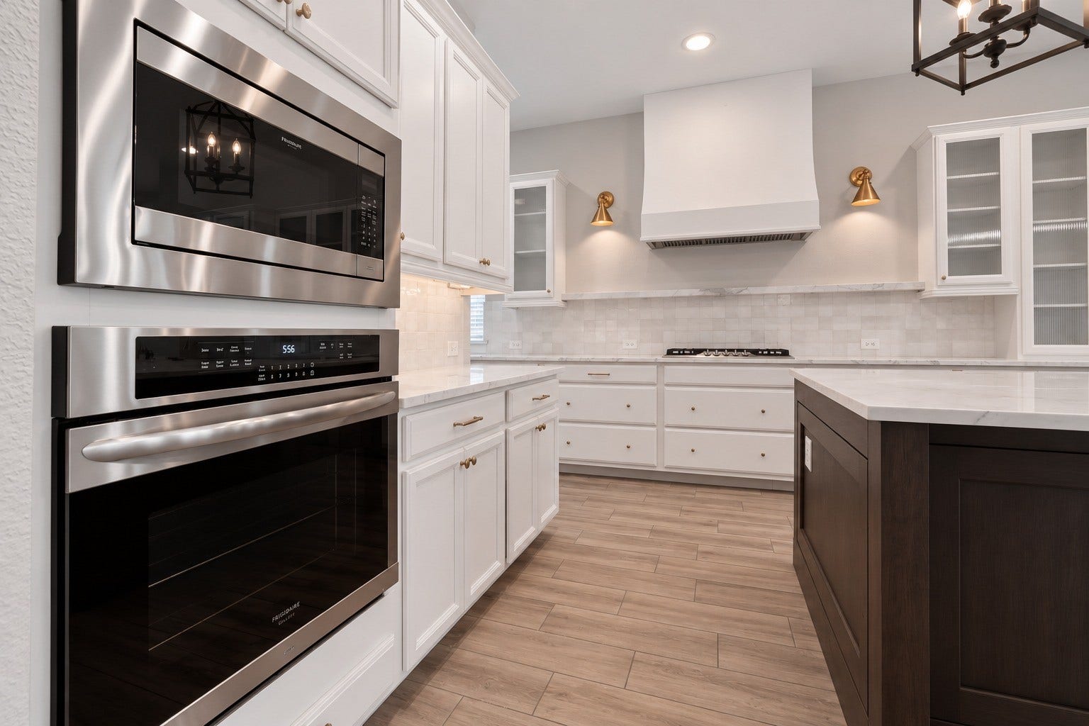 1515 Shining Willow Court, Richmond, TX 77406 Spacious gourmet kitchen featuring white cabinetry, quartz countertops, a large contrasting island, farmhouse sink, stainless steel appliances, and beautiful gold accents throughout.