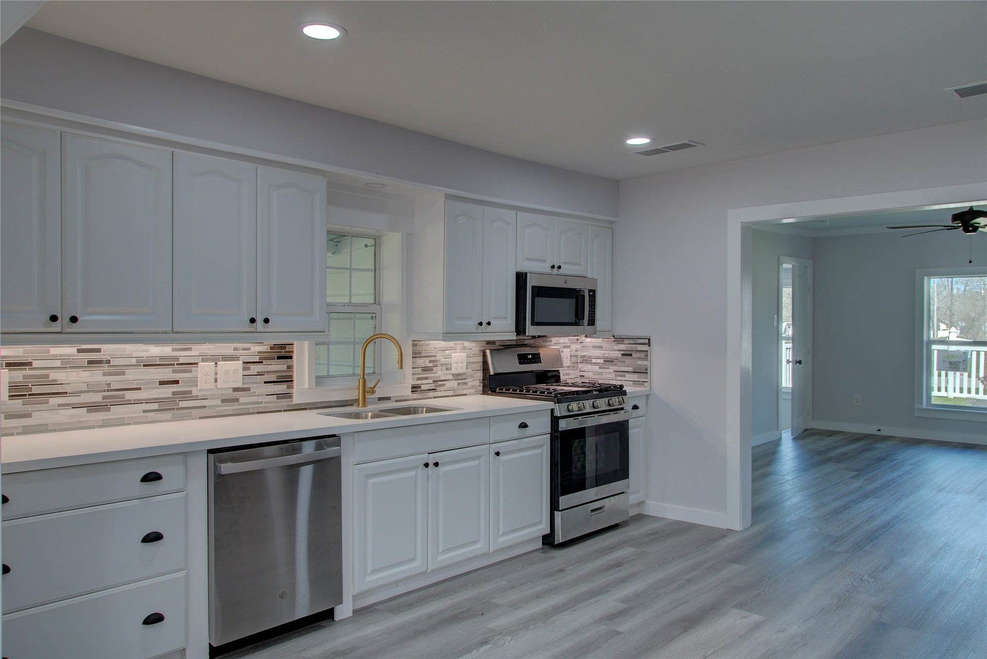 415 Perkins Avenue, League City, TX 77573 Modern kitchen featuring new stainless steel appliances, quartz countertops, a sleek glass tile backsplash, and under-cabinet lighting.