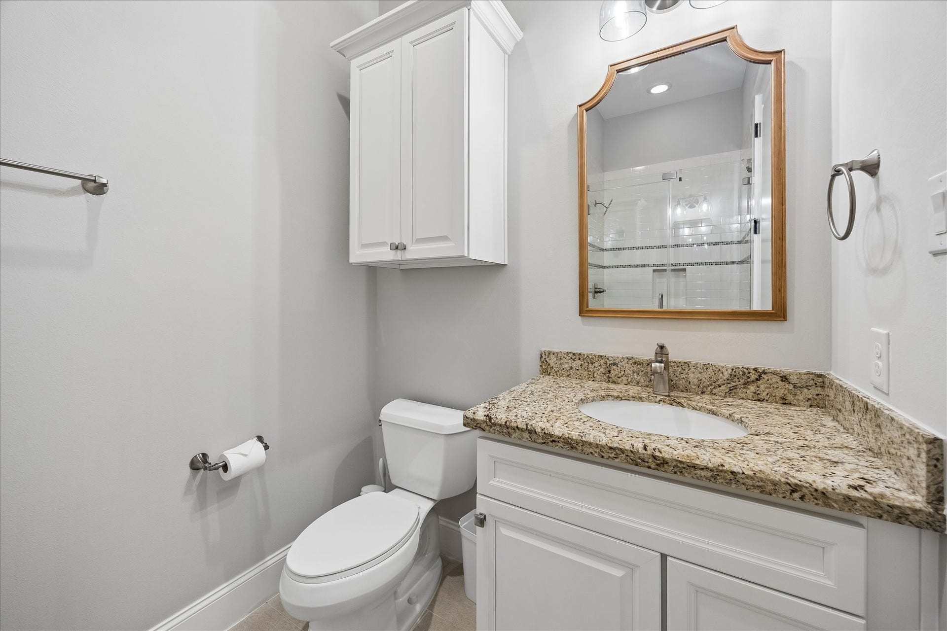 2915 Hicks Street, Houston, TX 77007 Elegant bathroom featuring a granite countertop, white cabinetry, and a framed mirror, offering a clean and modern aesthetic.