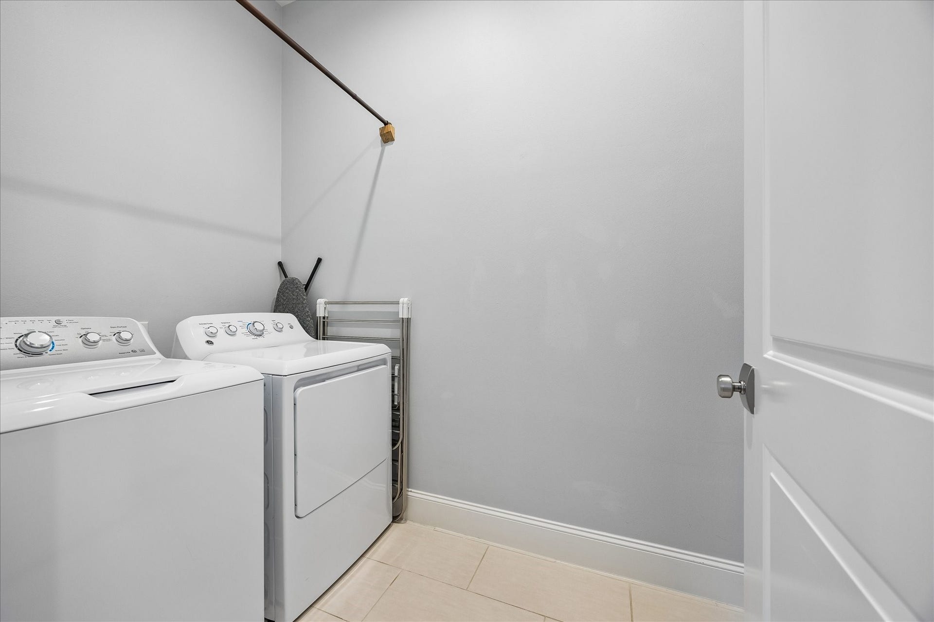 2915 Hicks Street, Houston, TX 77007 Modern laundry room with tile flooring, featuring a washer and dryer set against soft gray walls for a clean and functional space.