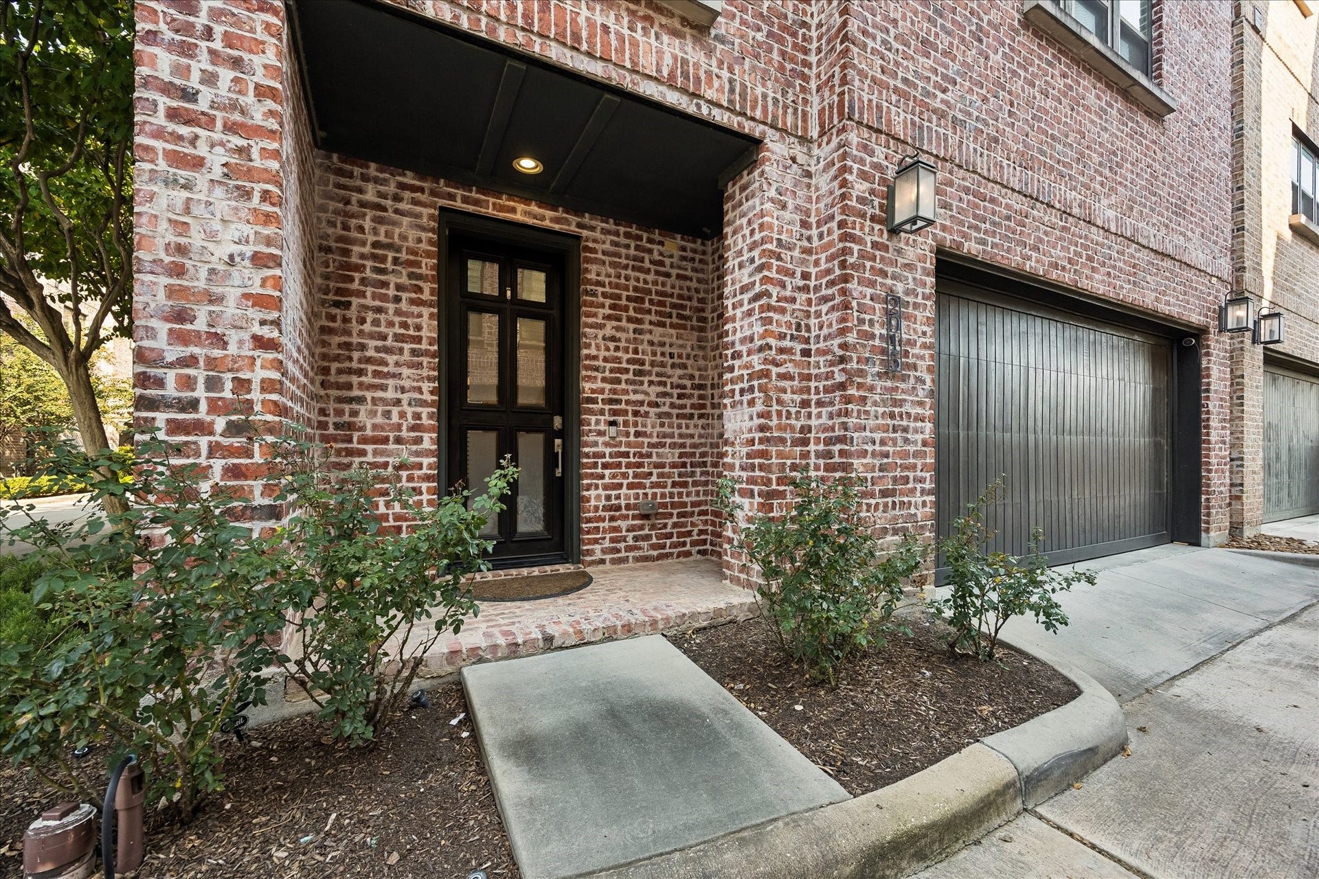2915 Hicks Street, Houston, TX 77007 Charming brick exterior with a welcoming front porch, complemented by lush greenery and a sleek garage door.