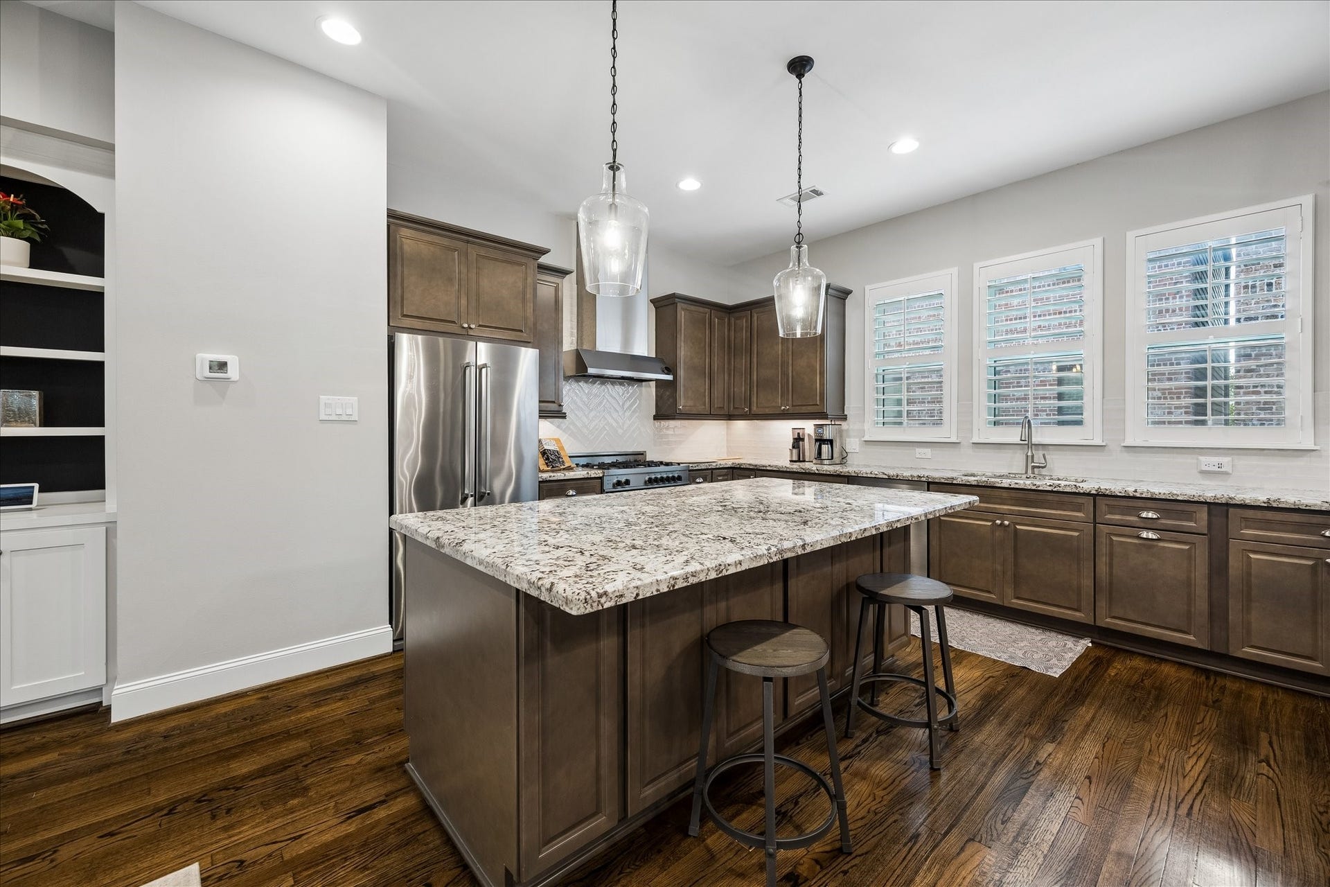 2915 Hicks Street, Houston, TX 77007 Experience culinary elegance in this spacious kitchen, featuring granite countertops, stainless steel appliances, and rich wooden cabinetry, complemented by stylish pendant lighting.
