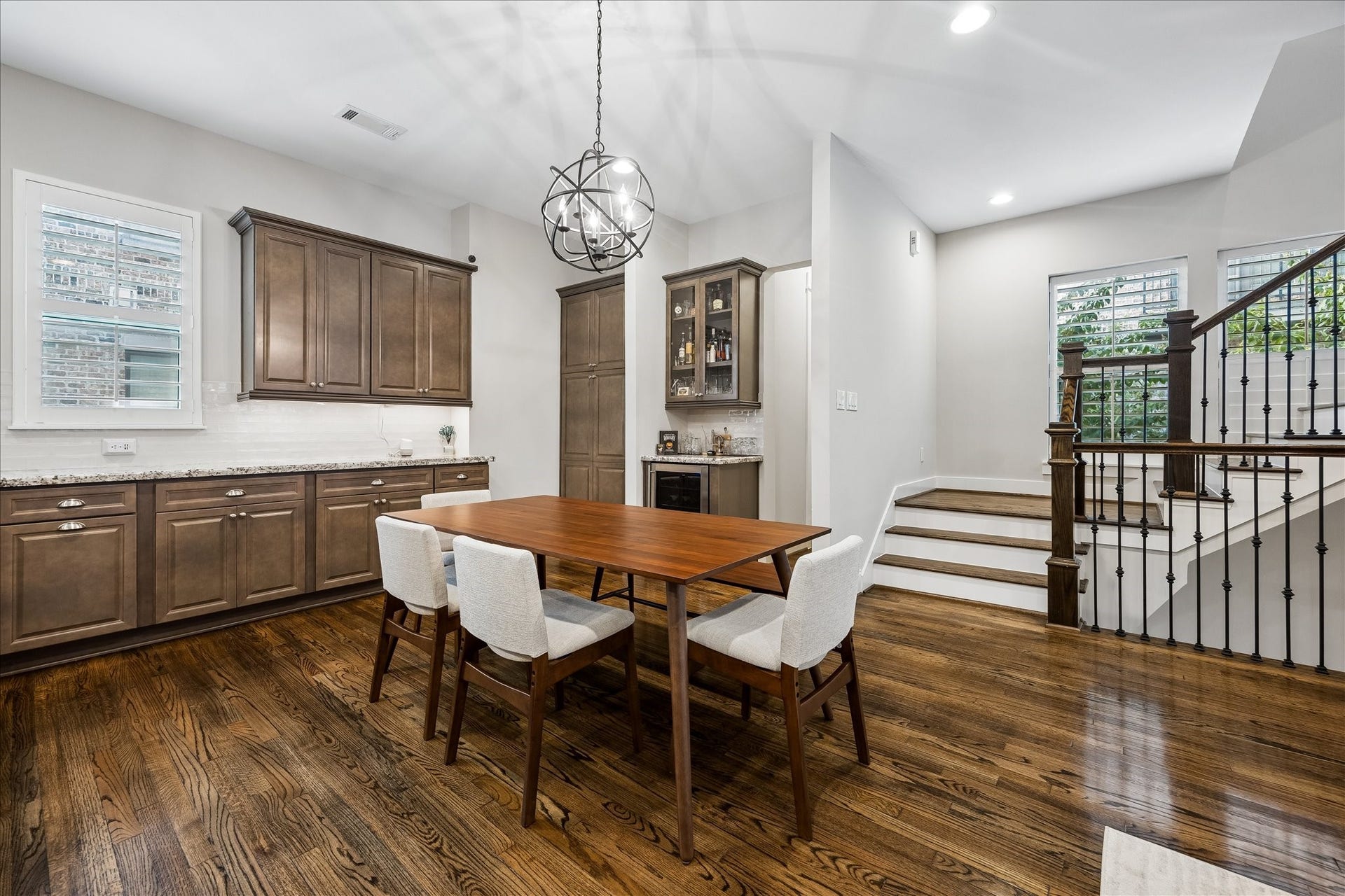 2915 Hicks Street, Houston, TX 77007 Charming dining area with rich hardwood floors, elegant cabinetry, and a striking modern chandelier. The space seamlessly connects to a staircase, enhancing the open-concept feel.