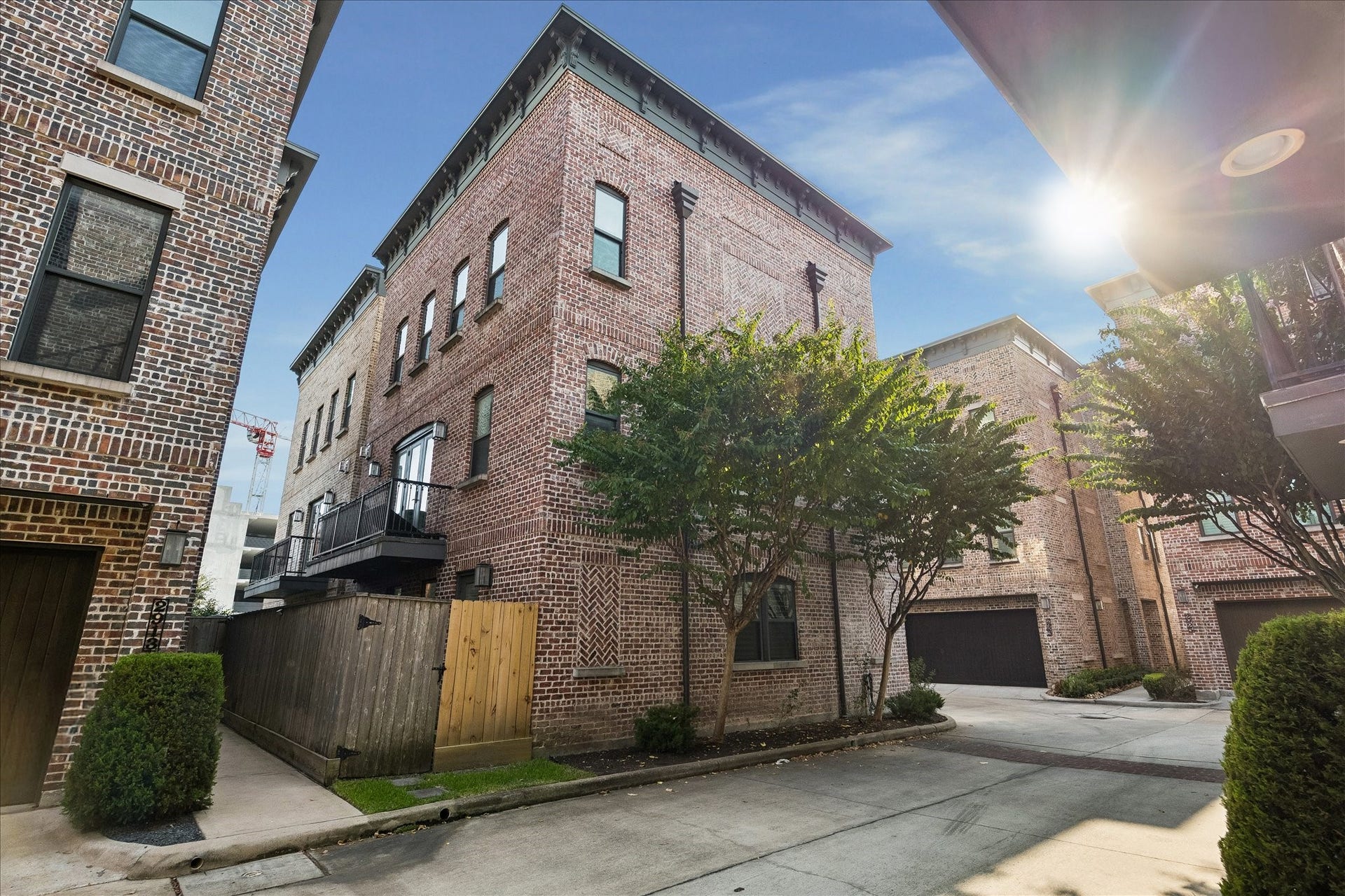 2915 Hicks Street, Houston, TX 77007 Charming brick townhome nestled in a serene courtyard setting, featuring lush greenery and a private balcony.