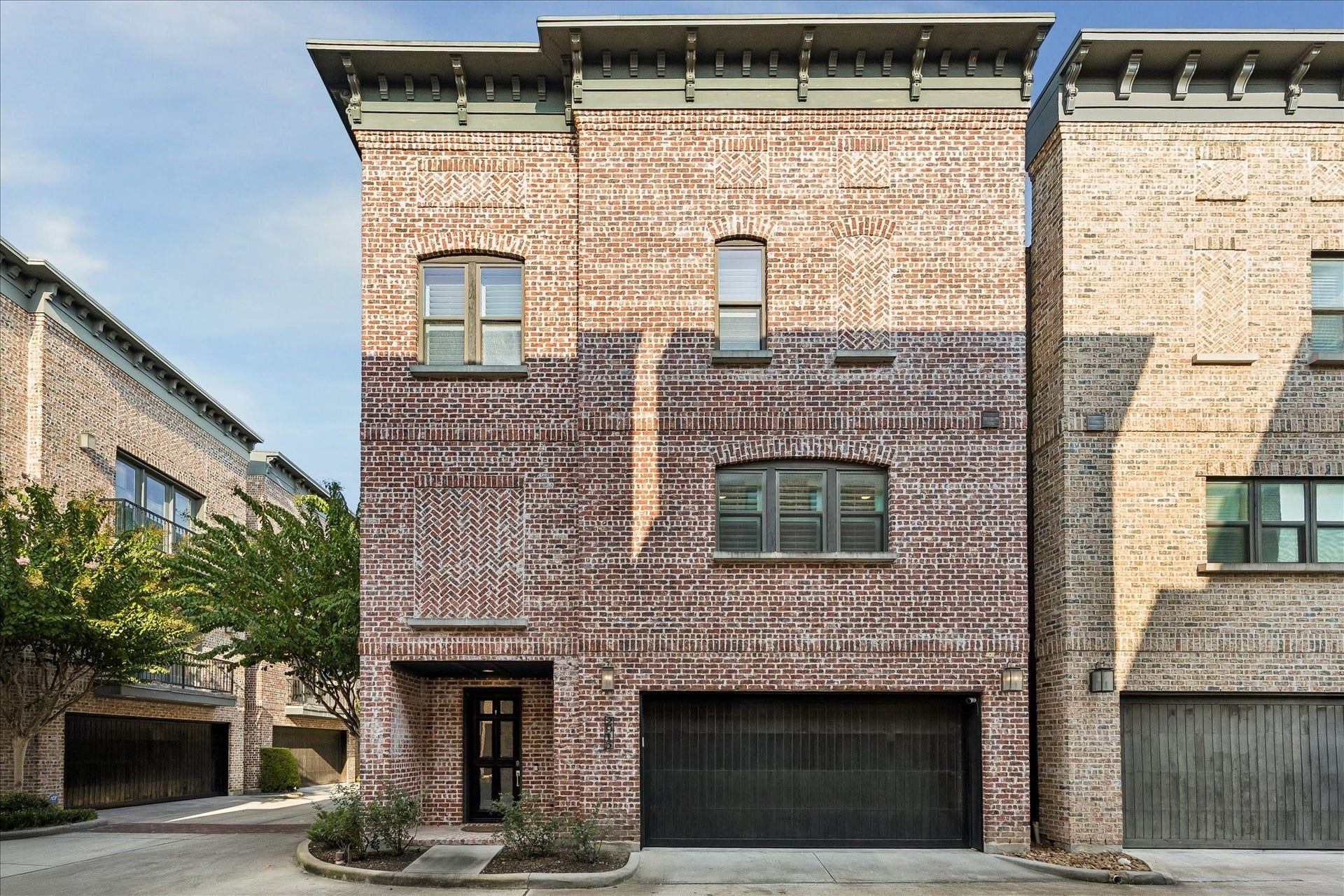 2915 Hicks Street, Houston, TX 77007 Stunning three-story brick townhouse featuring a spacious two-car garage and elegant arched windows, offering a blend of classic design and modern functionality.
