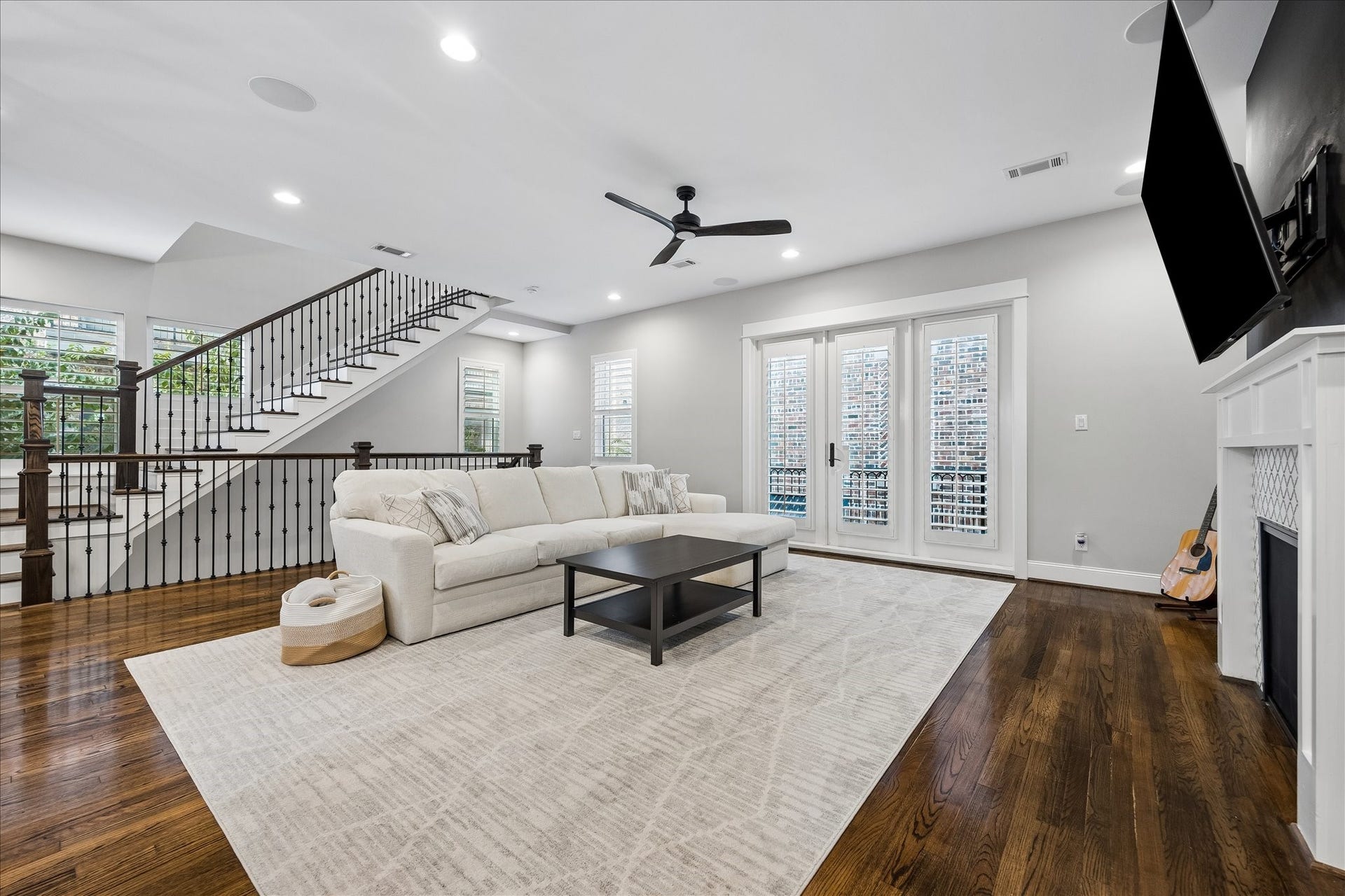 2915 Hicks Street, Houston, TX 77007 Spacious living room with elegant hardwood floors, a cozy fireplace, and abundant natural light streaming through large windows and French doors with plantation shutters