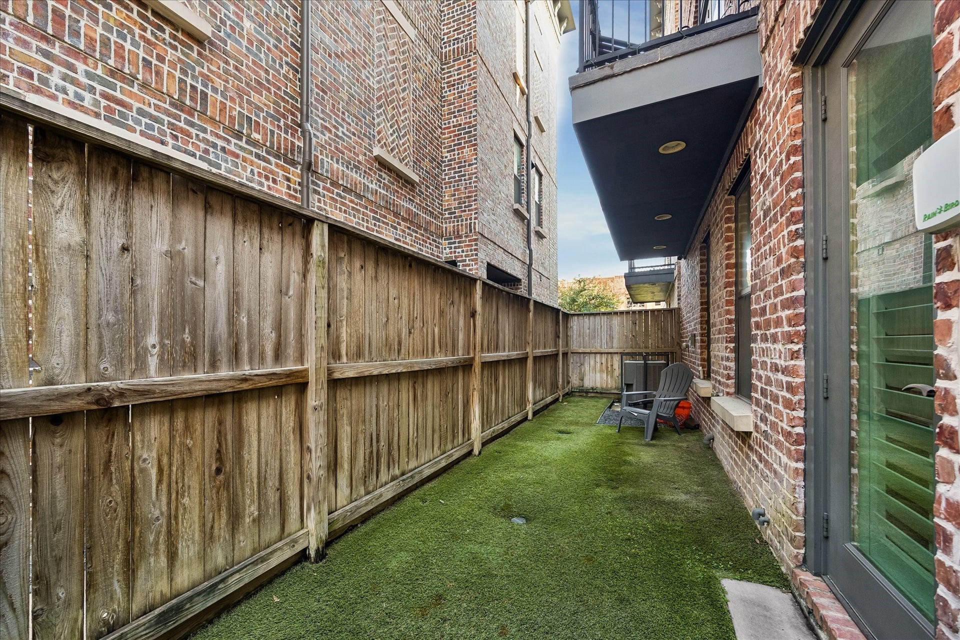 2915 Hicks Street, Houston, TX 77007 Cozy outdoor space with artificial turf, enclosed by a wooden fence and surrounded by charming brick walls, perfect for relaxation and privacy.
