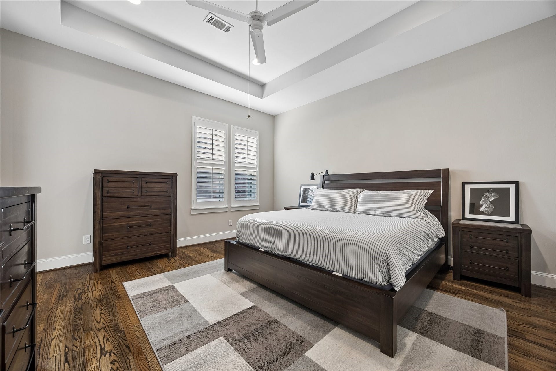 2915 Hicks Street, Houston, TX 77007 Spacious primary bedroom with elegant tray ceiling, featuring a modern ceiling fan and large windows with plantation shutters.