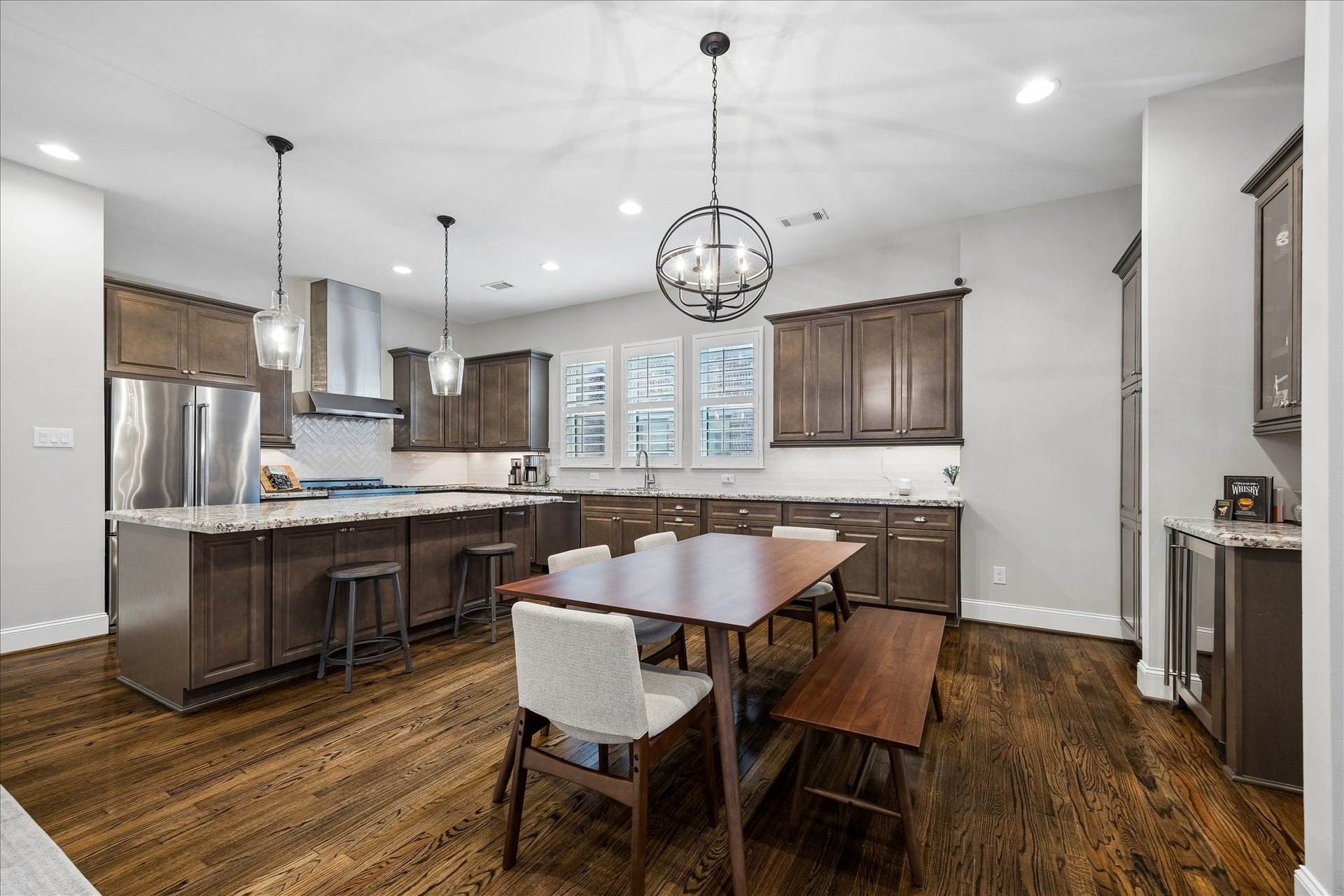 2915 Hicks Street, Houston, TX 77007 Spacious kitchen with elegant dark wood cabinetry, a large center island, and modern stainless steel appliances, complemented by stylish pendant lighting and a cozy dining area.