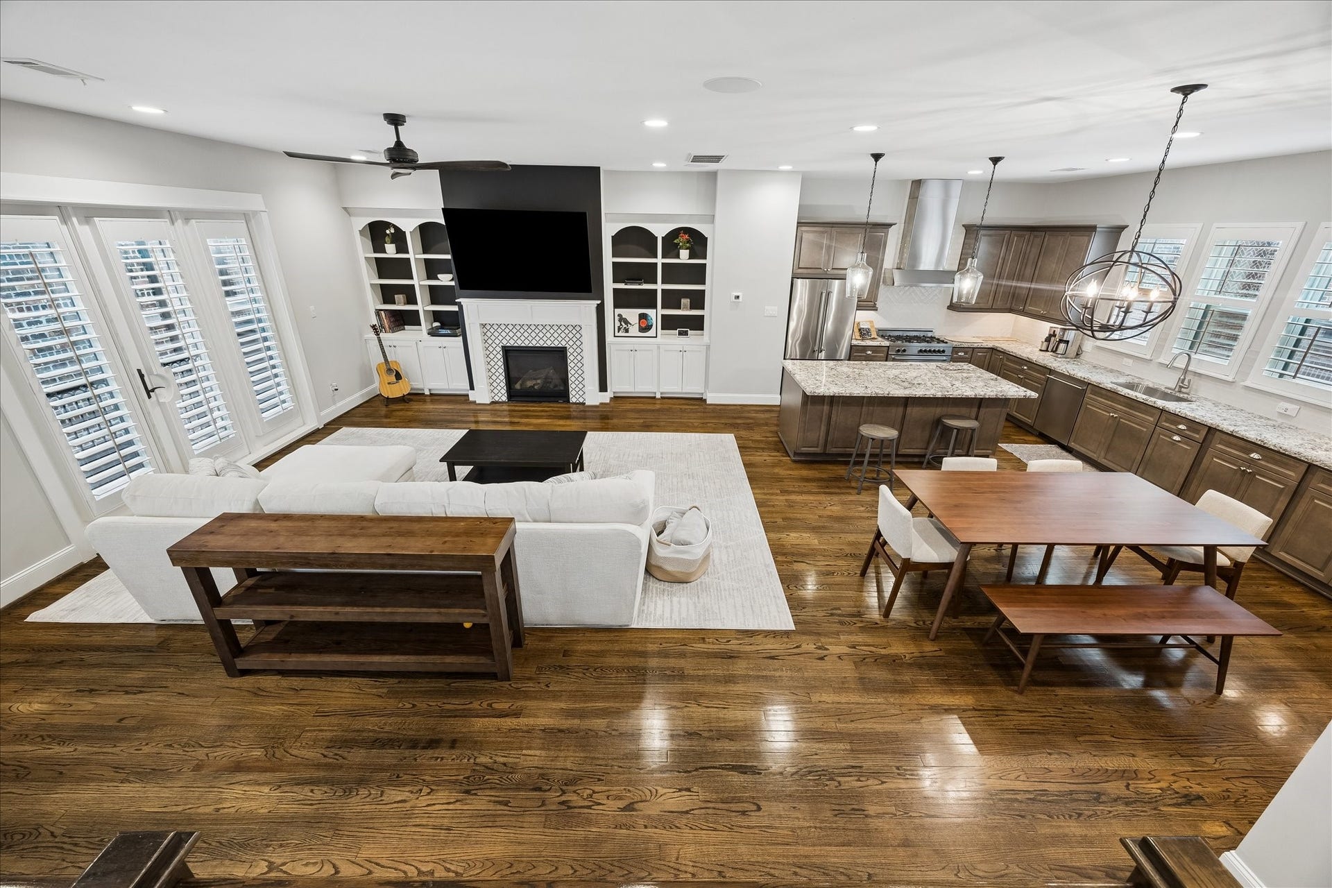 2915 Hicks Street, Houston, TX 77007 Spacious open-concept living area with elegant hardwood floors, featuring a cozy fireplace, built-in shelving, and a modern kitchen with granite countertops and stainless steel appliances.