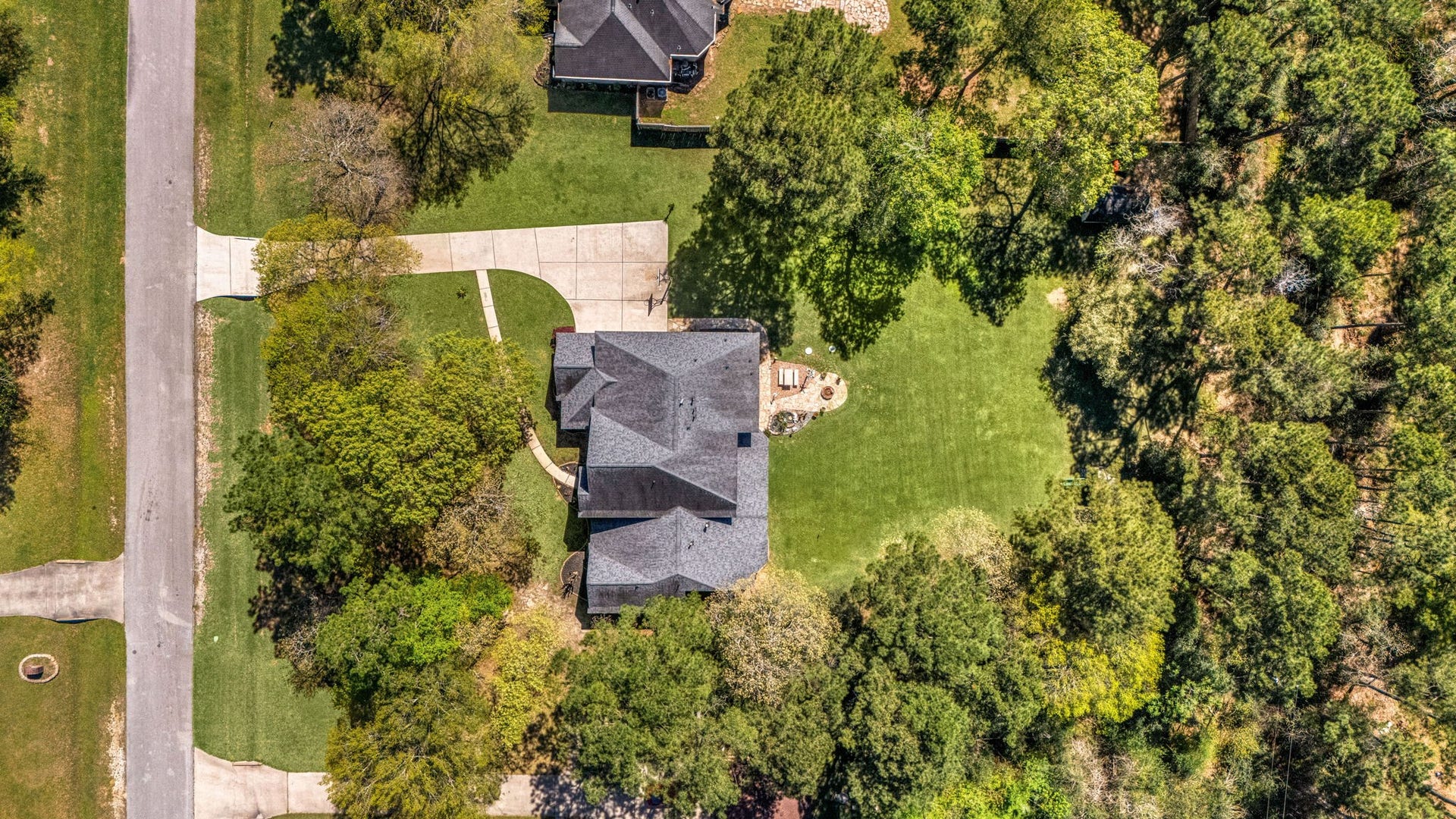 Aerial view showing the expansive lot surrounded by mature trees, offering privacy, space, and a beautiful natural setting.