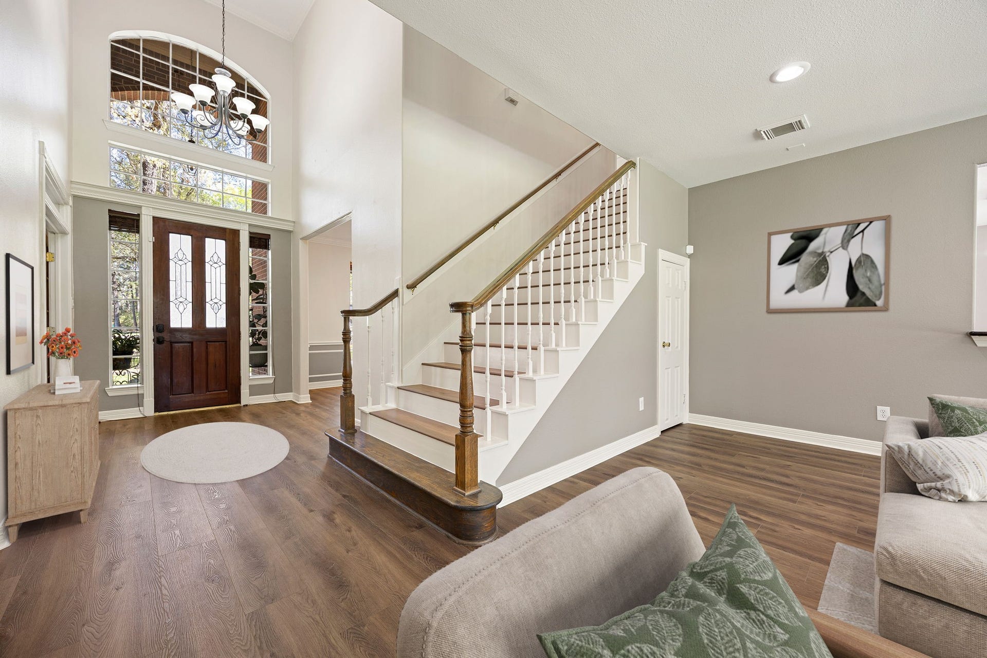 Impressive foyer featuring soaring ceilings, abundant natural light, and a classic staircase that adds charm and character to the home. *virtually staged*