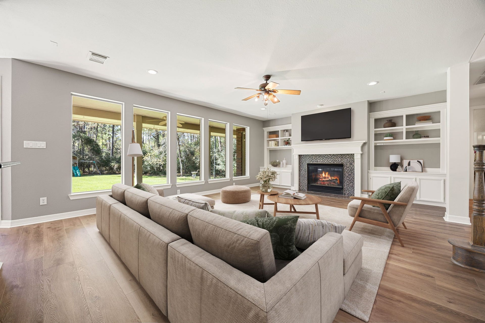 Spacious living area filled with natural light featuring large windows, beautiful built-ins, and a cozy fireplace that creates the perfect setting for relaxing or entertaining. The open layout and backyard views make this space feel bright, warm, and inviting. *virtually staged*