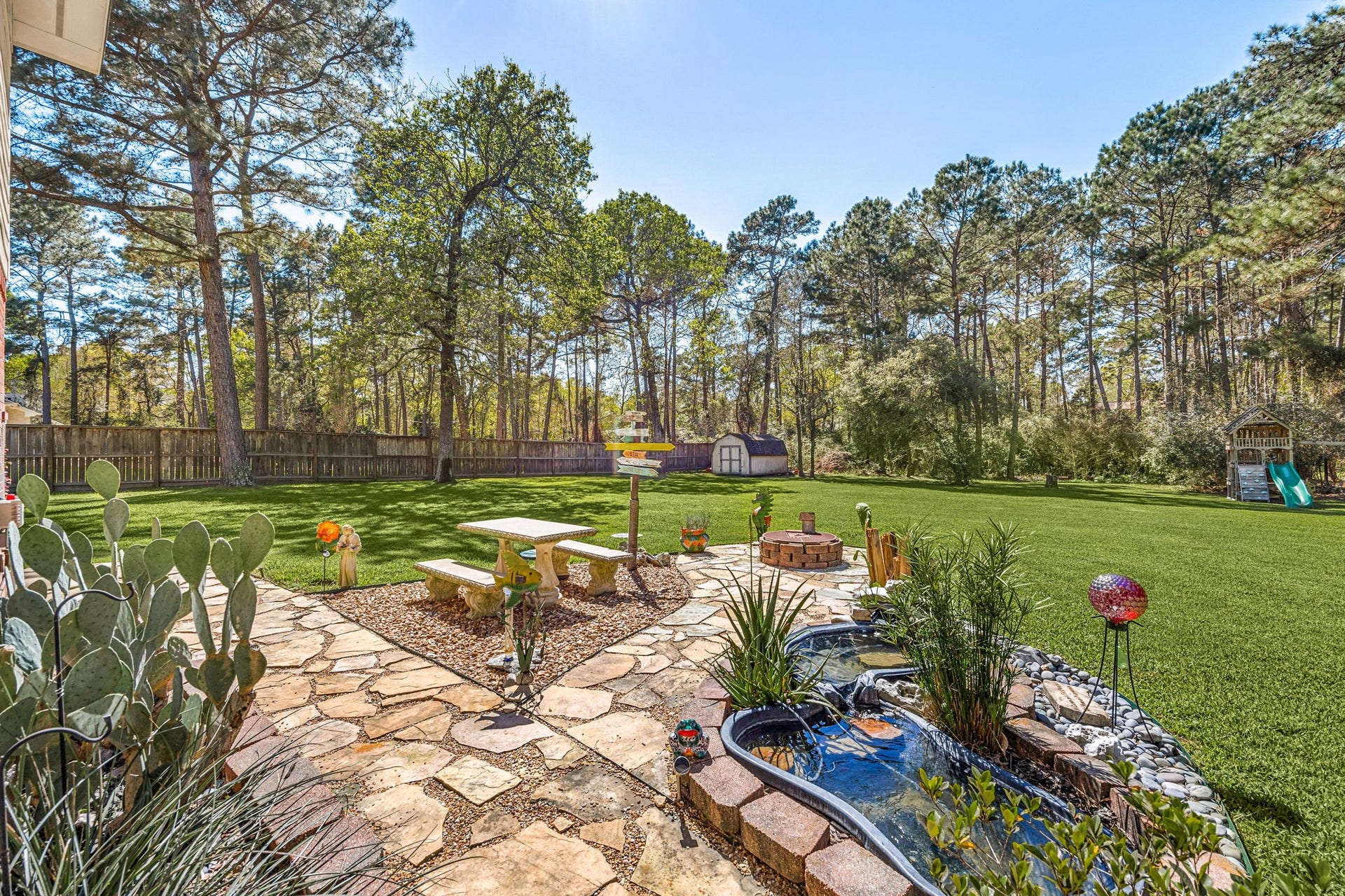Enjoy outdoor living in this spacious backyard with stone patio, decorative garden area, and plenty of room for entertaining or relaxing in a private setting.