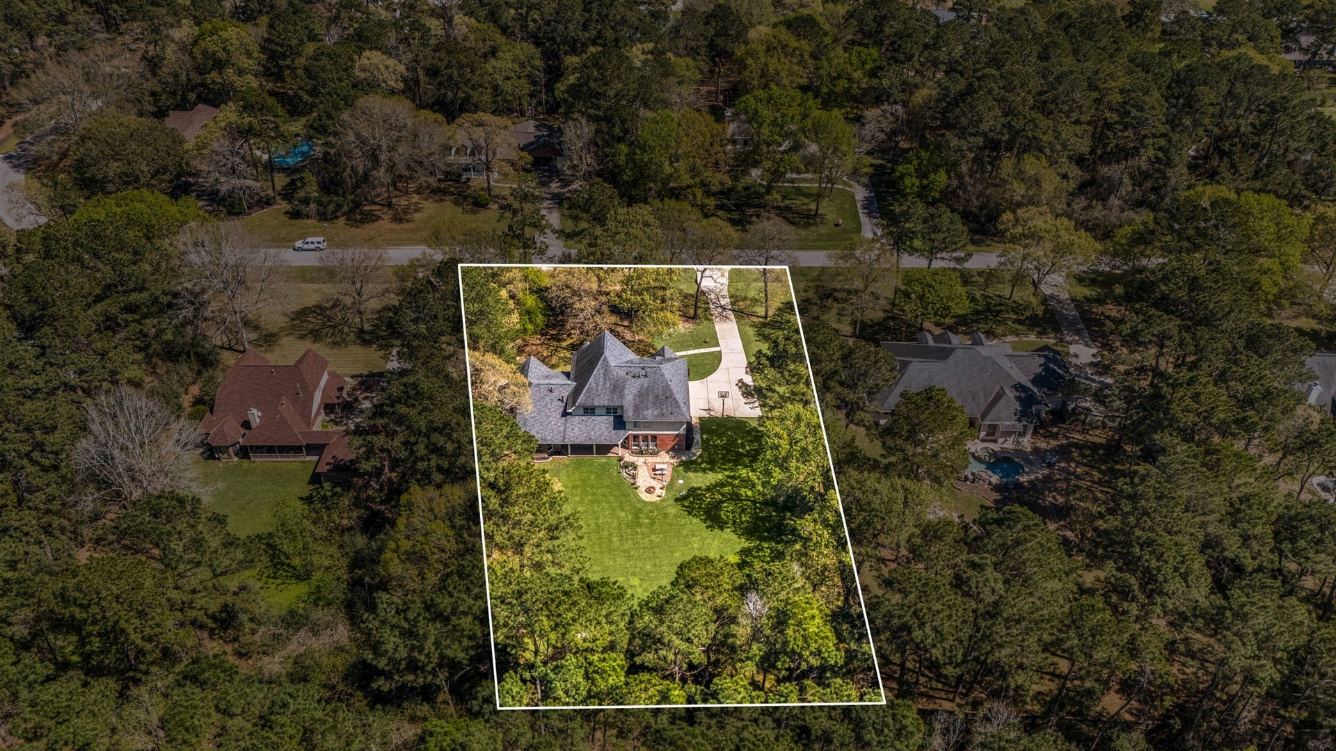 Aerial view with property boundaries outlined, showcasing the large homesite surrounded by mature trees and offering a private, spacious setting.