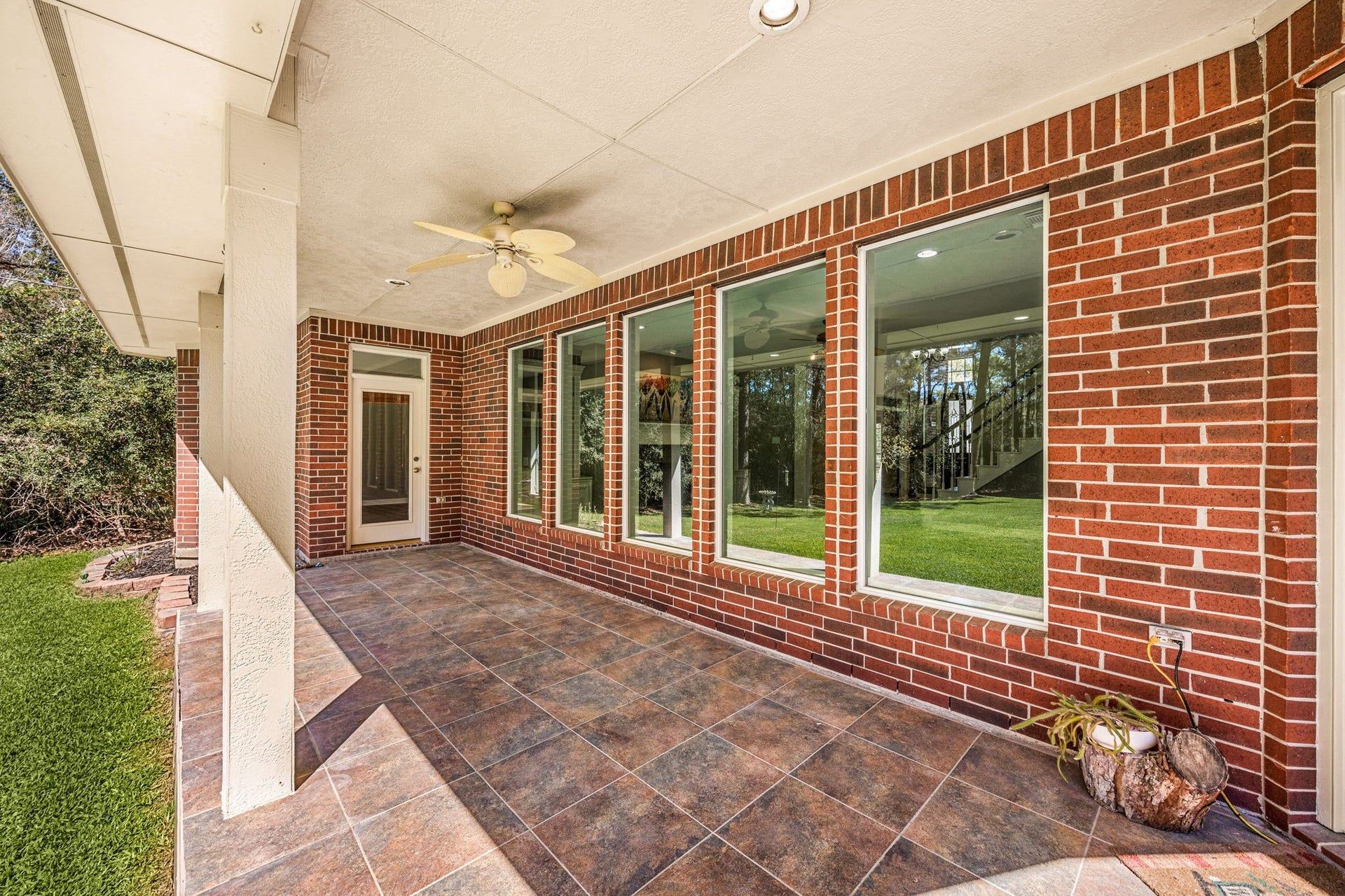 Enjoy outdoor living under the covered patio featuring ceiling fan, brick exterior, and plenty of space for seating and gatherings.