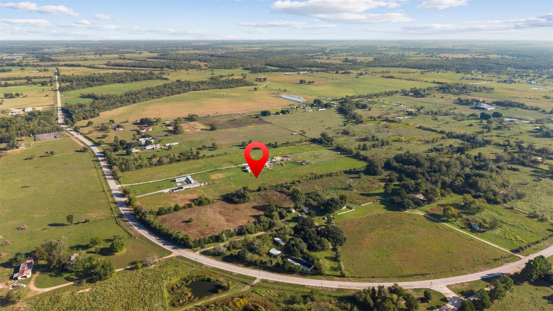 Northeast-facing aerial highlighting the property's location along FM 1887 and its connection to the surrounding network of country roads, neighboring acreage, and agricultural land.