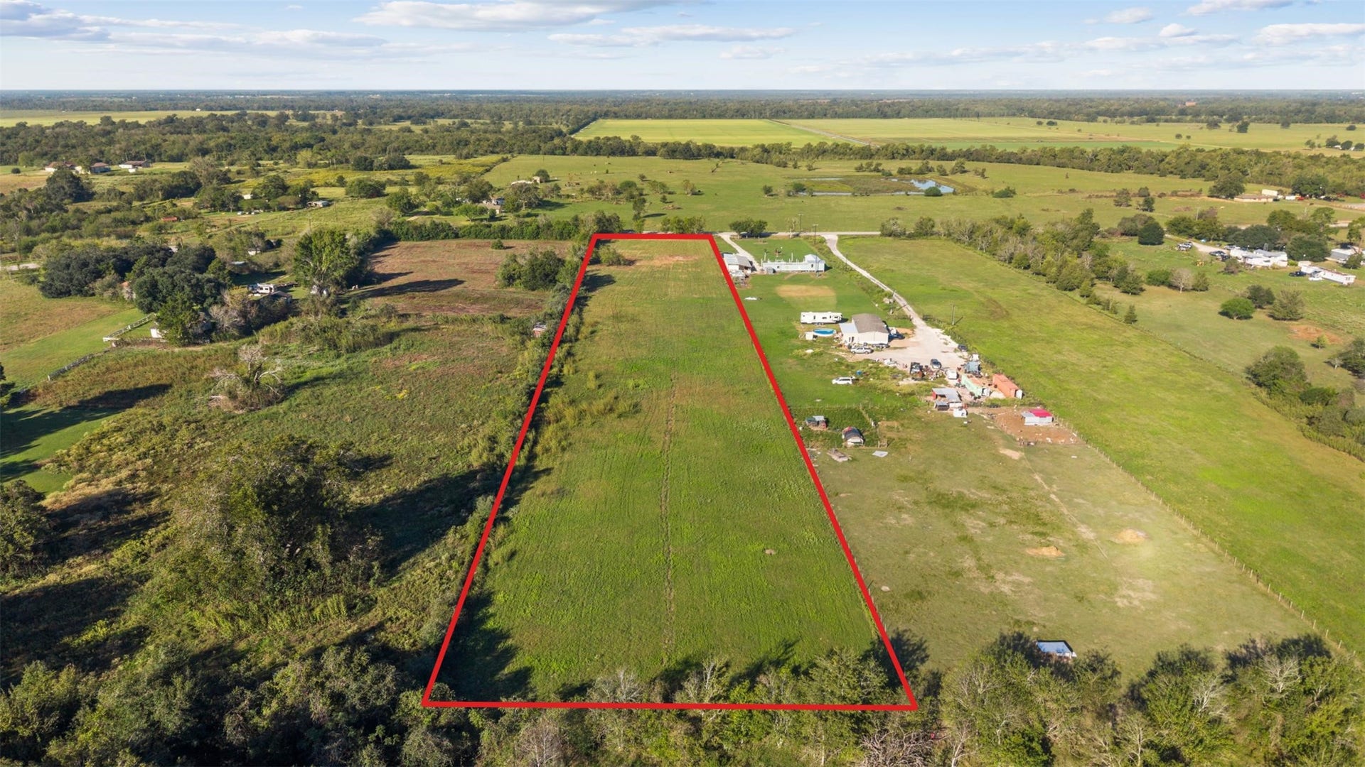 A west-facing aerial perspective highlighting the property's position among neighboring acreage tracts, open pastures, and the scenic countryside surrounding Hempstead.