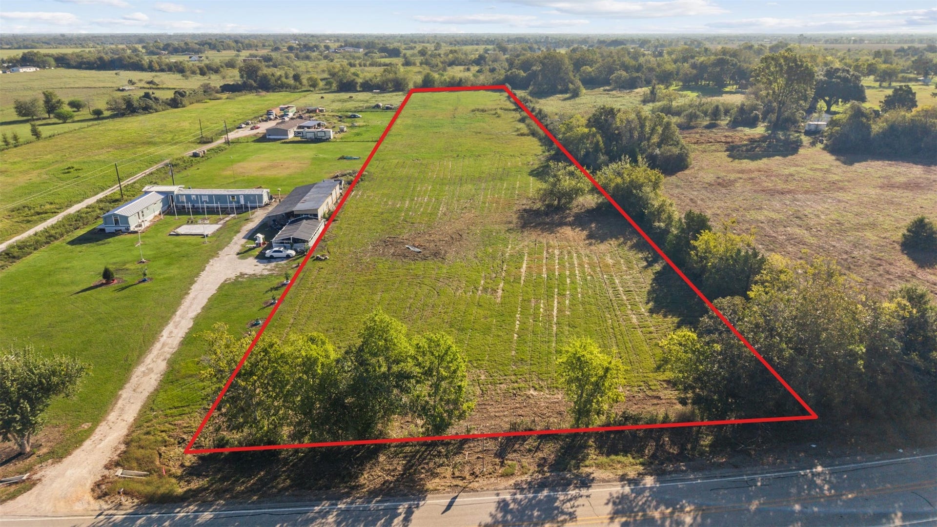Aerial view facing east, showcasing the property's approximate boundaries, generous road frontage, and the surrounding countryside of Waller County.