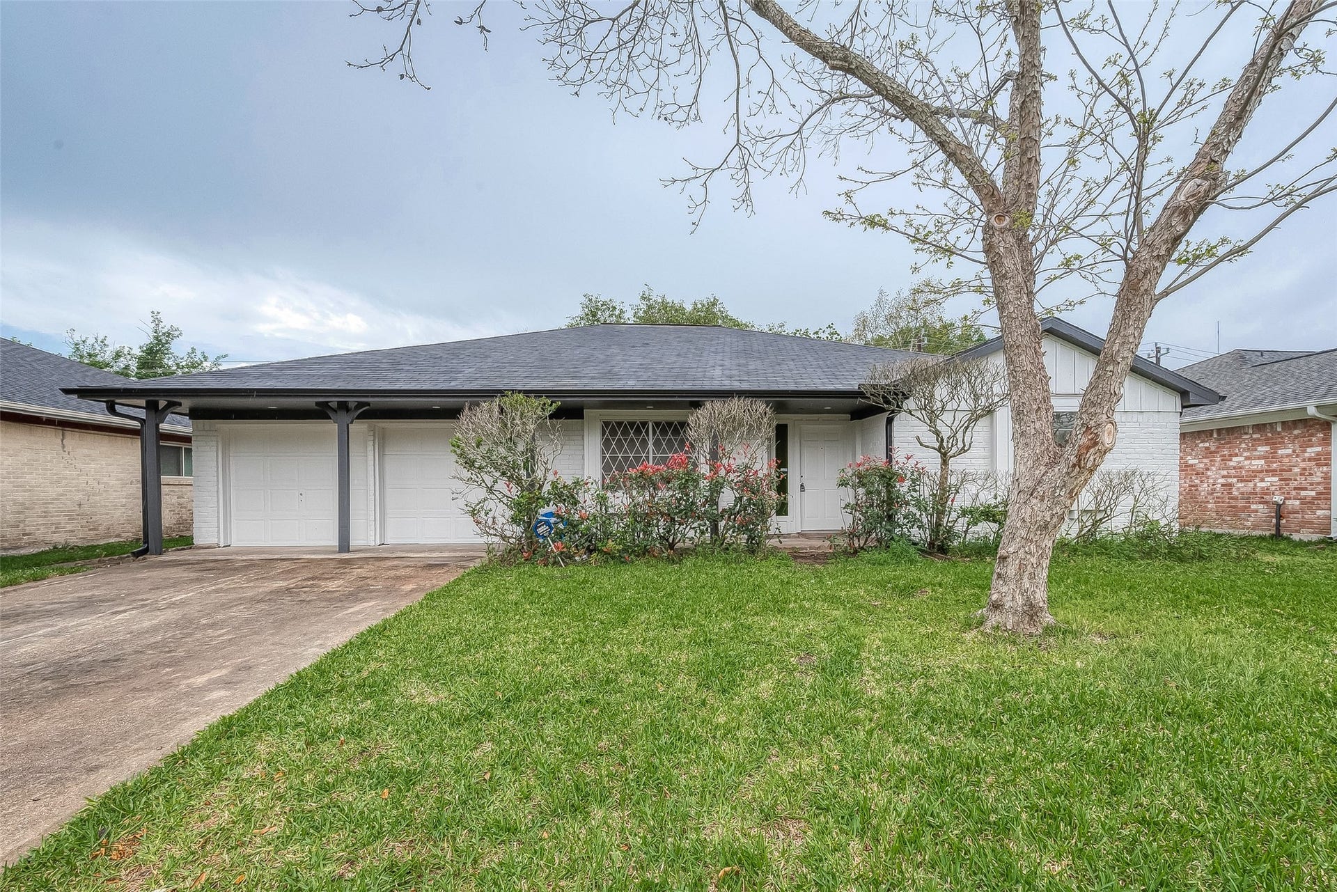 Charming single-story home with a welcoming front yard, mature tree, and a spacious two-car garage.