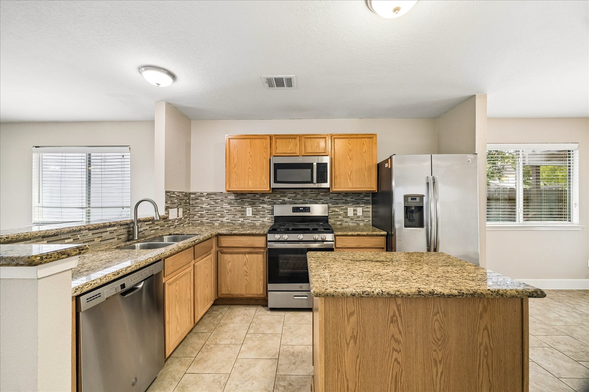 10819 Cobblecreek Way, Missouri City, TX 77459 This beautifully updated kitchen brings together granite counters, stylish tile backsplash, sleek stainless-steel appliances, a handy center island for meal prep, and bar seating at the dining room for chats with the chef while dinner is underway.