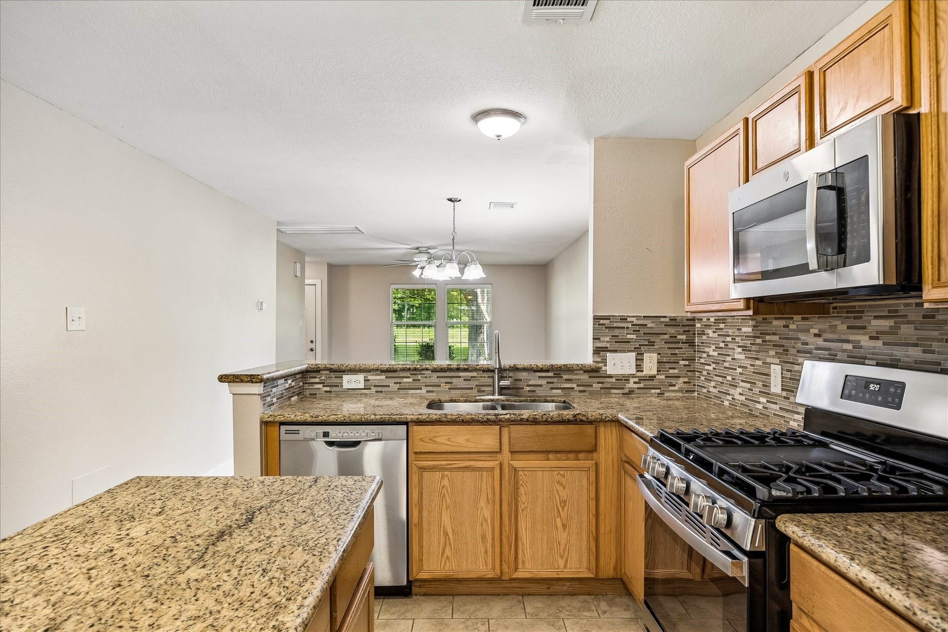 10819 Cobblecreek Way, Missouri City, TX 77459 Granite counters, gorgeous tile backsplash, sleek stainless-steel appliances, a center prep island, a sunny breakfast area, and bar seating come together in a practical kitchen designed for everyday cooking, gathering, and easy living.