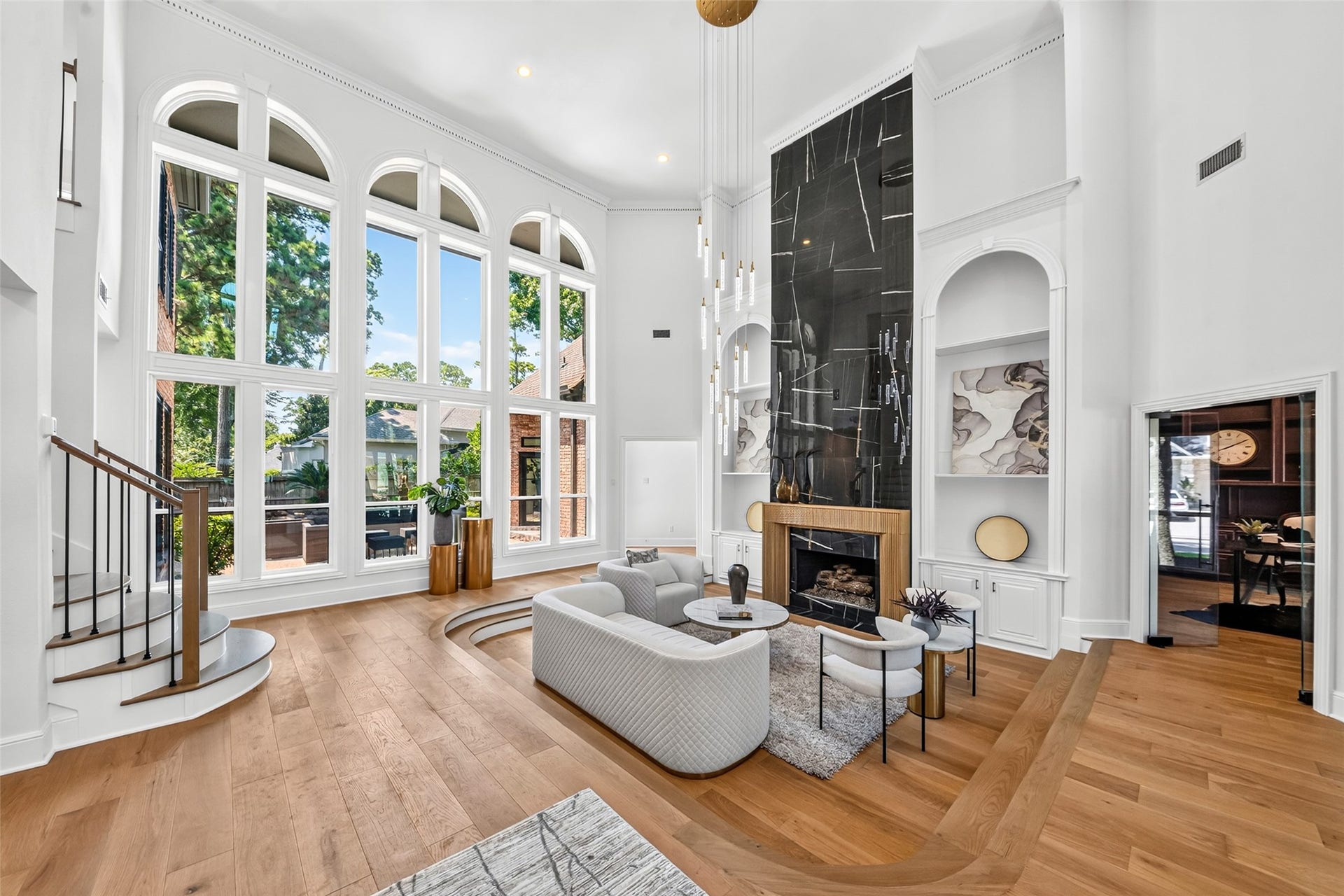 46 Pebble Cove Drive, The Woodlands, TX 77381 Expansive living room with soaring ceilings, dramatic floor-to-ceiling windows, and a stunning modern fireplace, offering an abundance of natural light and stylish comfort.