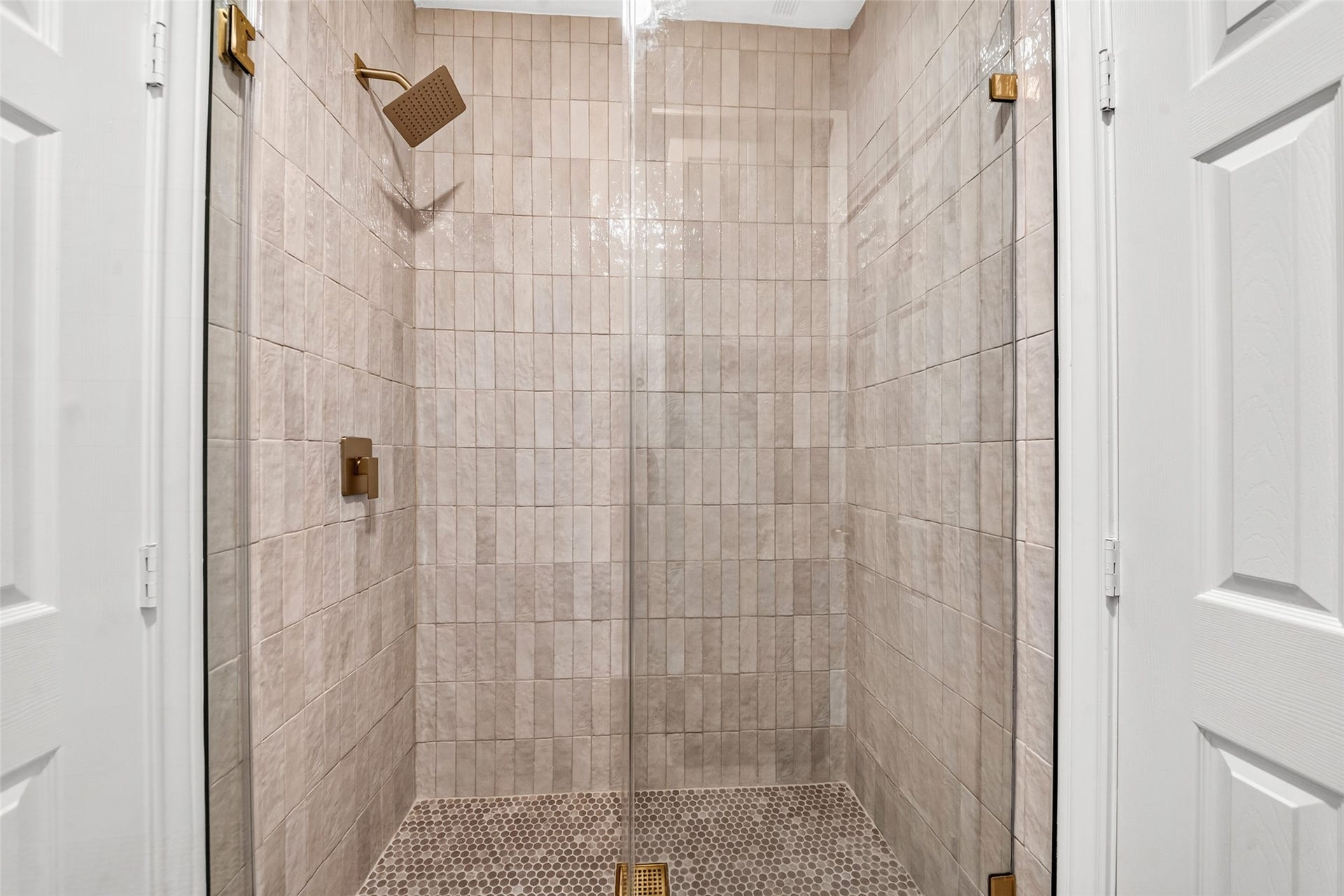 46 Pebble Cove Drive, The Woodlands, TX 77381 Elegant shower featuring sleek beige tiles, a modern glass door, and a stylish rainfall showerhead for a luxurious bathing experience.
