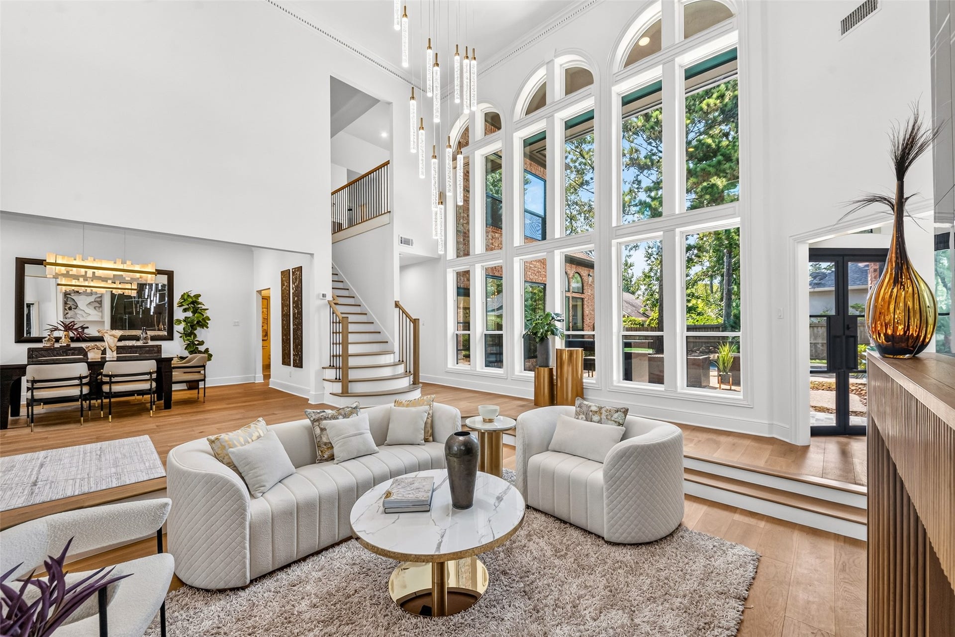 46 Pebble Cove Drive, The Woodlands, TX 77381 Experience luxury living in this stunning space featuring soaring ceilings and expansive windows that flood the room with natural light. The open floor plan seamlessly connects the elegant living area to a sophisticated dining space, perfect for entertaining.