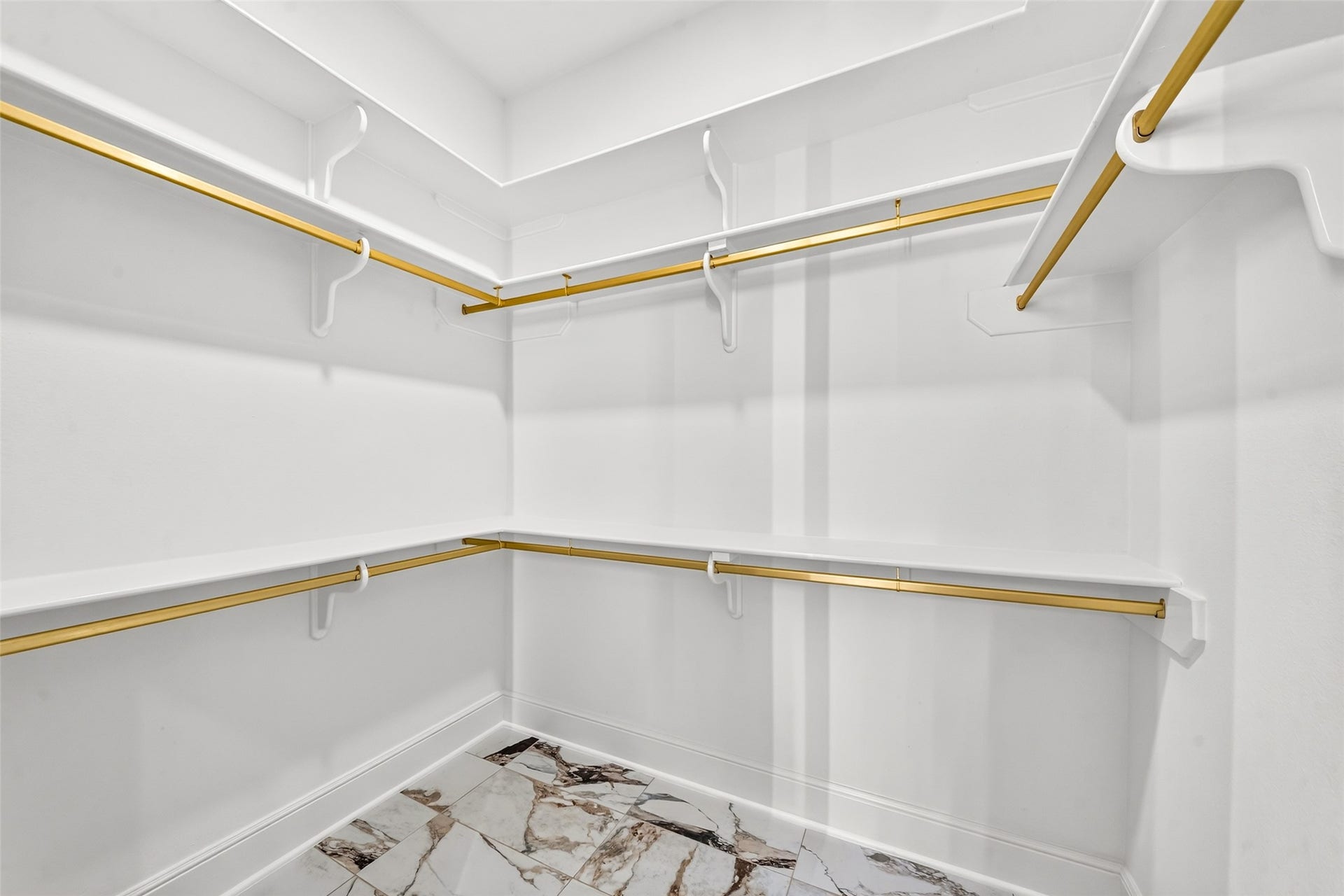 46 Pebble Cove Drive, The Woodlands, TX 77381 Experience luxury and organization with two expansive closets featuring elegant gold accents and sleek marble flooring, perfect for stylish living.