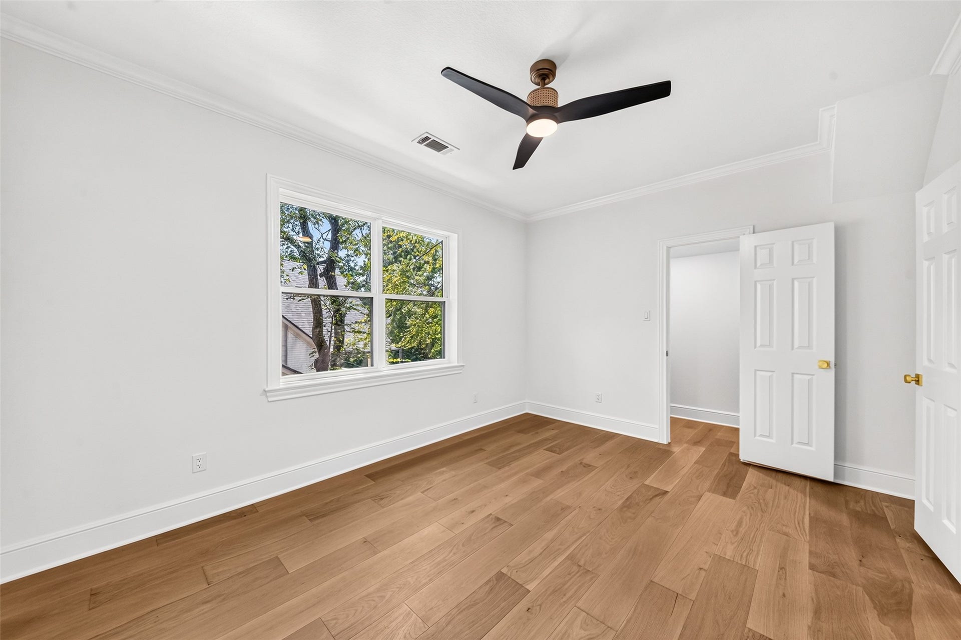 46 Pebble Cove Drive, The Woodlands, TX 77381 Bright and airy bedroom featuring elegant hardwood floors, a modern ceiling fan, and a large window providing abundant natural light.