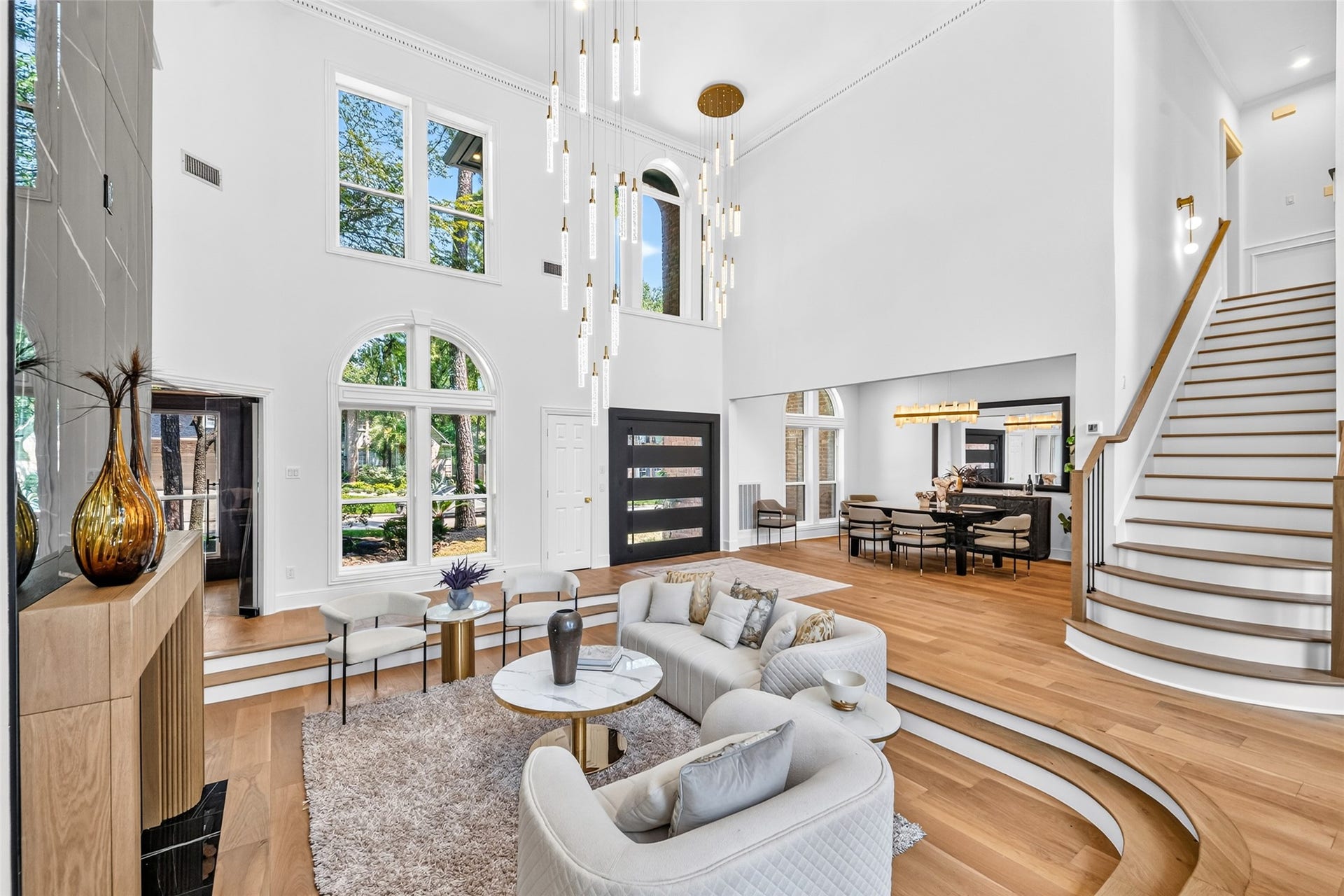 46 Pebble Cove Drive, The Woodlands, TX 77381 Ascending the elegant staircase, you're greeted by a breathtaking view of the expansive, light-filled living area with soaring ceilings and modern design.