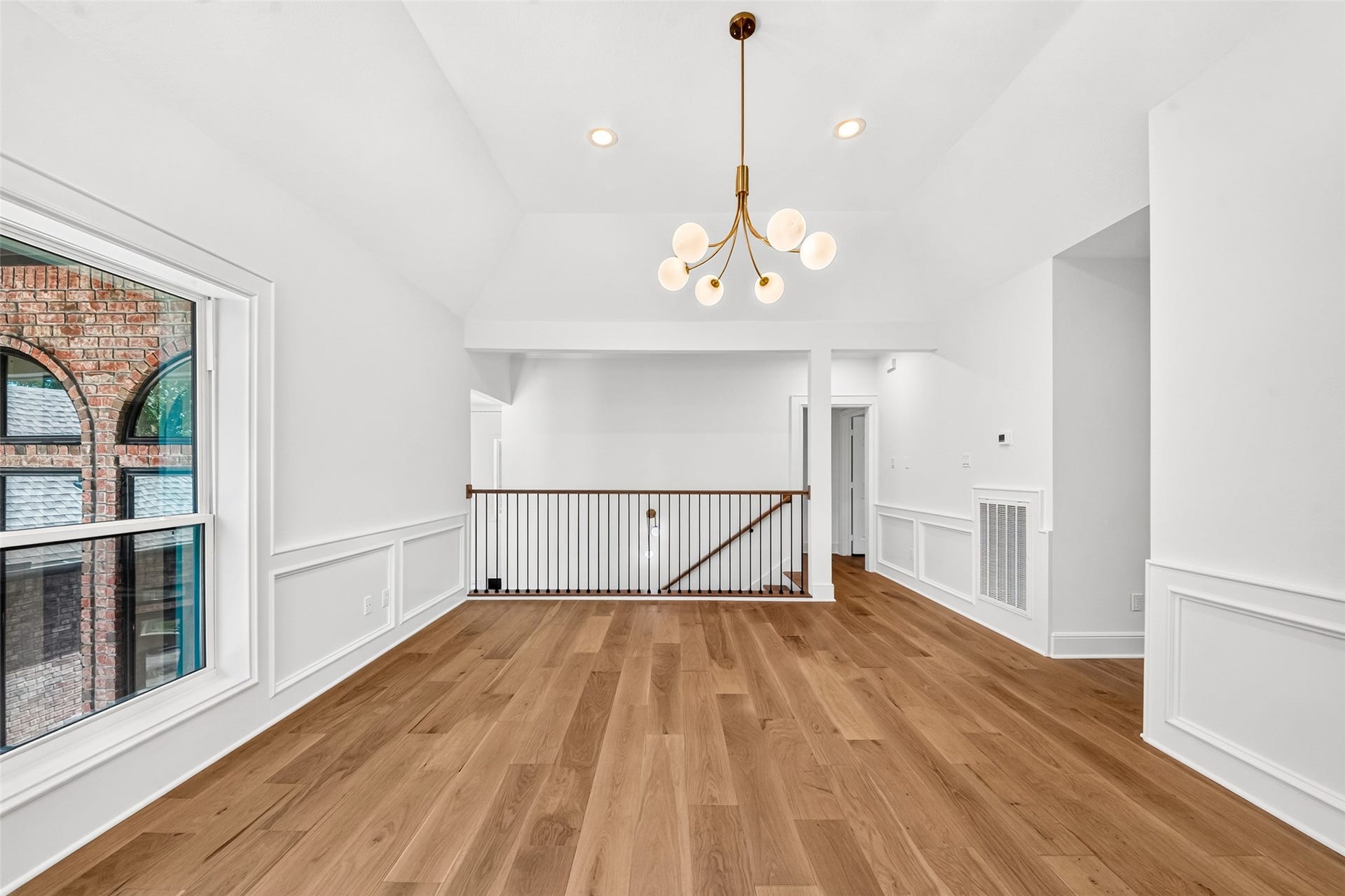 46 Pebble Cove Drive, The Woodlands, TX 77381 Bright and open area featuring elegant hardwood floors, a stylish modern chandelier, and crisp white walls, perfect for a versatile living or dining space.
