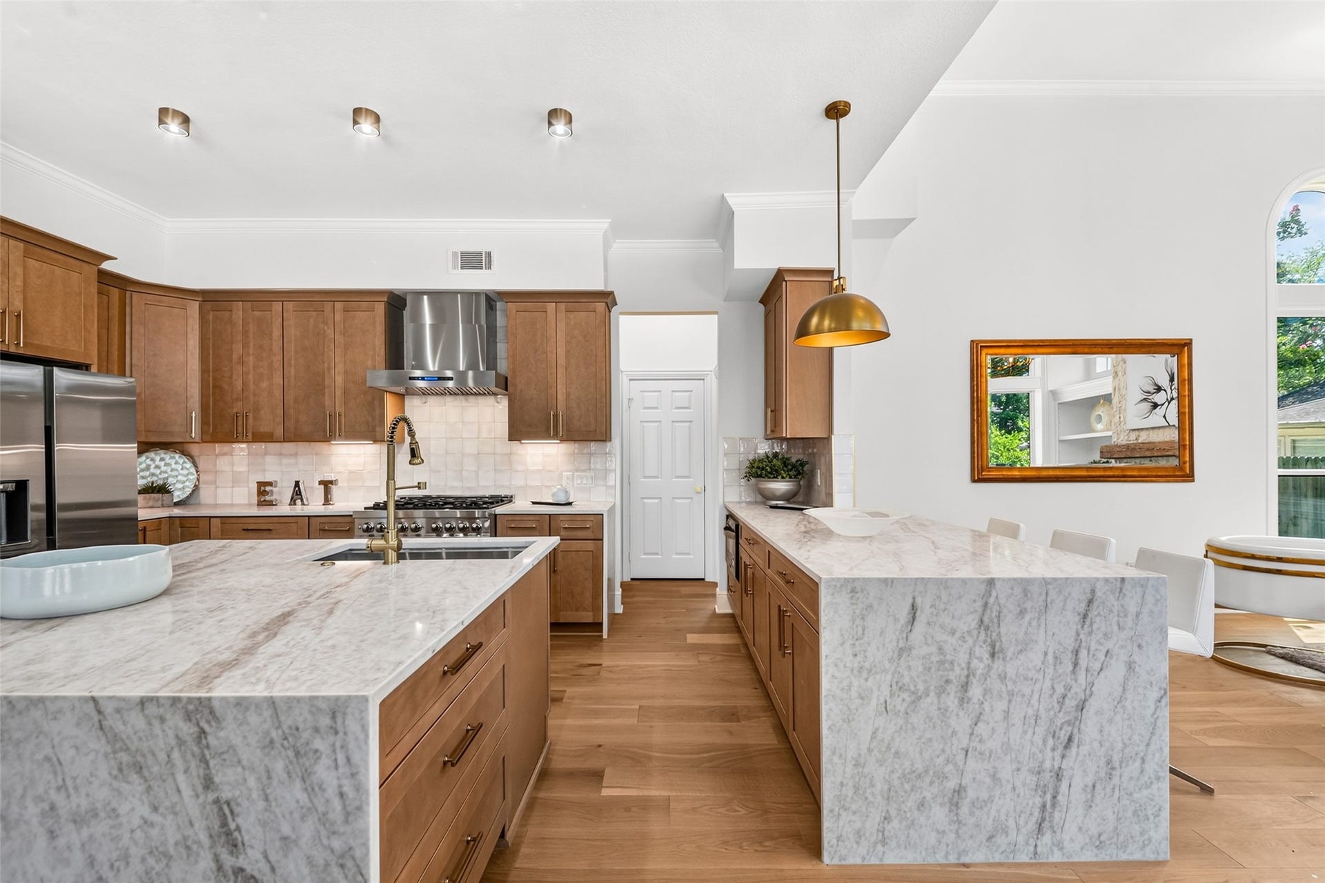 46 Pebble Cove Drive, The Woodlands, TX 77381 Spacious kitchen with elegant marble countertops, warm wooden cabinetry, and stainless steel appliances, enhanced by a sleek range hood and modern lighting.