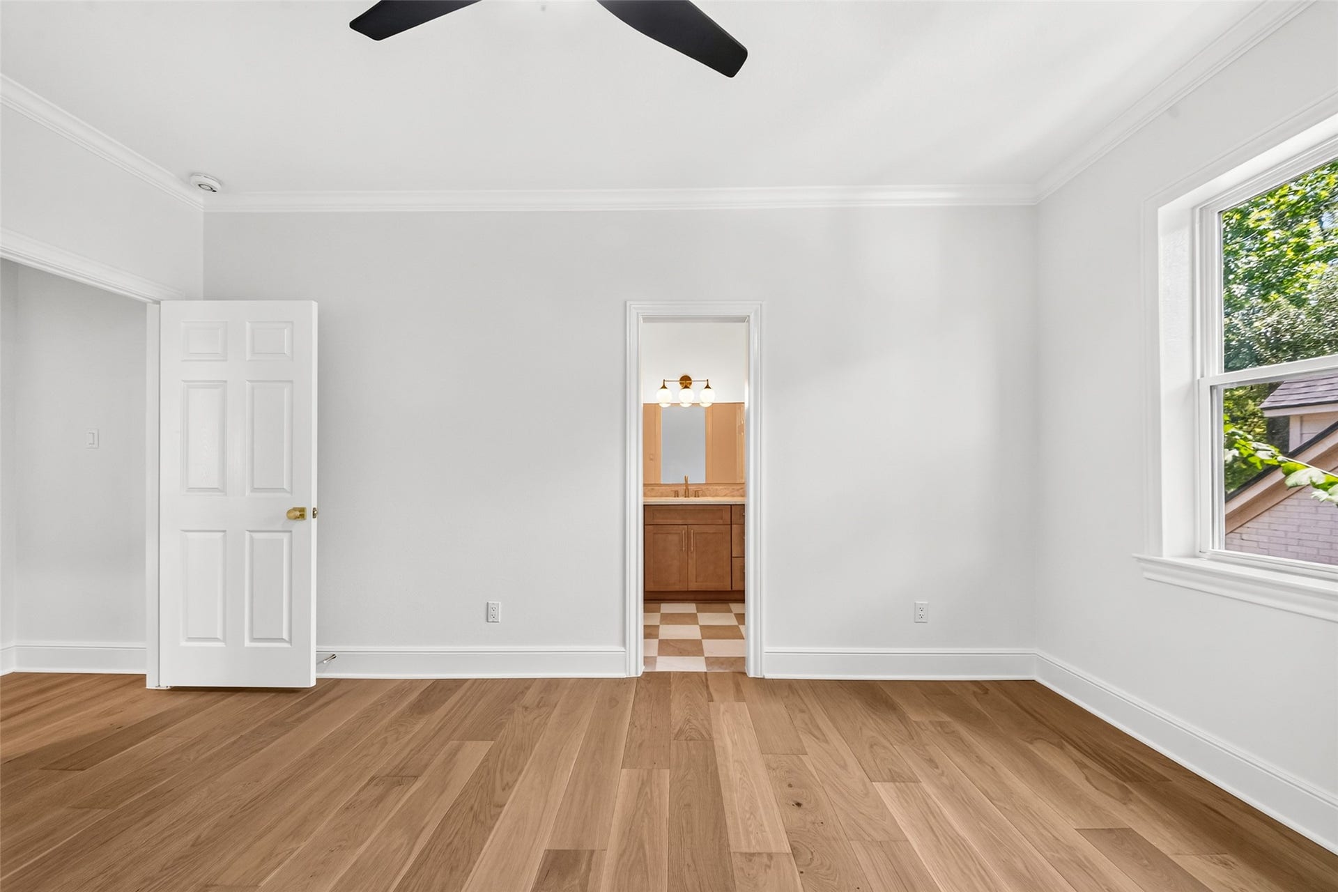 46 Pebble Cove Drive, The Woodlands, TX 77381 Upstairs, discover a bright and inviting bedroom featuring elegant wood flooring, a stylish ceiling fan, and ample natural light.