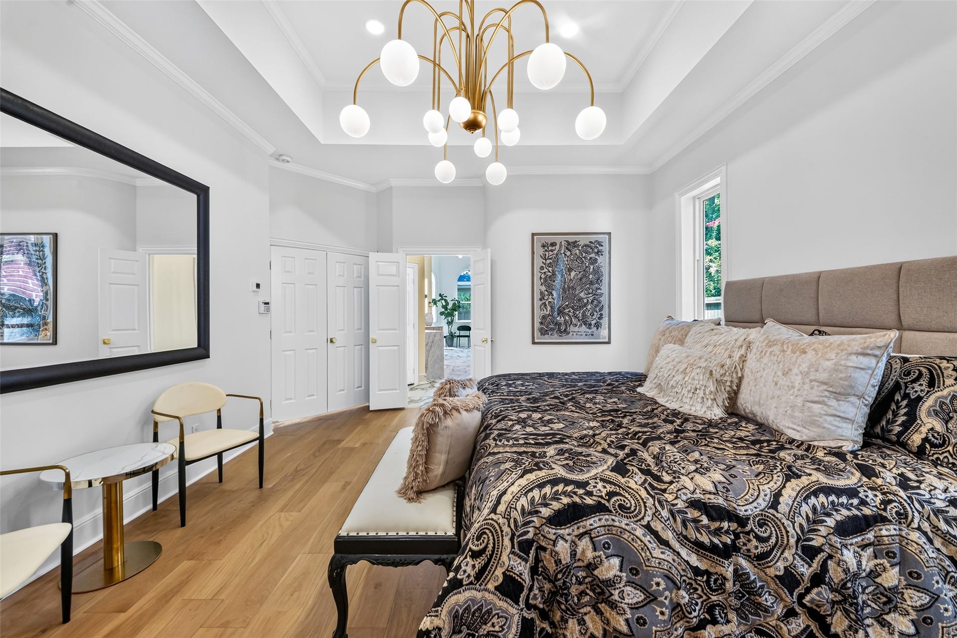 46 Pebble Cove Drive, The Woodlands, TX 77381 Elegant bedroom featuring a luxurious bed with plush bedding, a stylish chandelier, and hardwood floors. Bright and airy with modern decor and ample closet space.